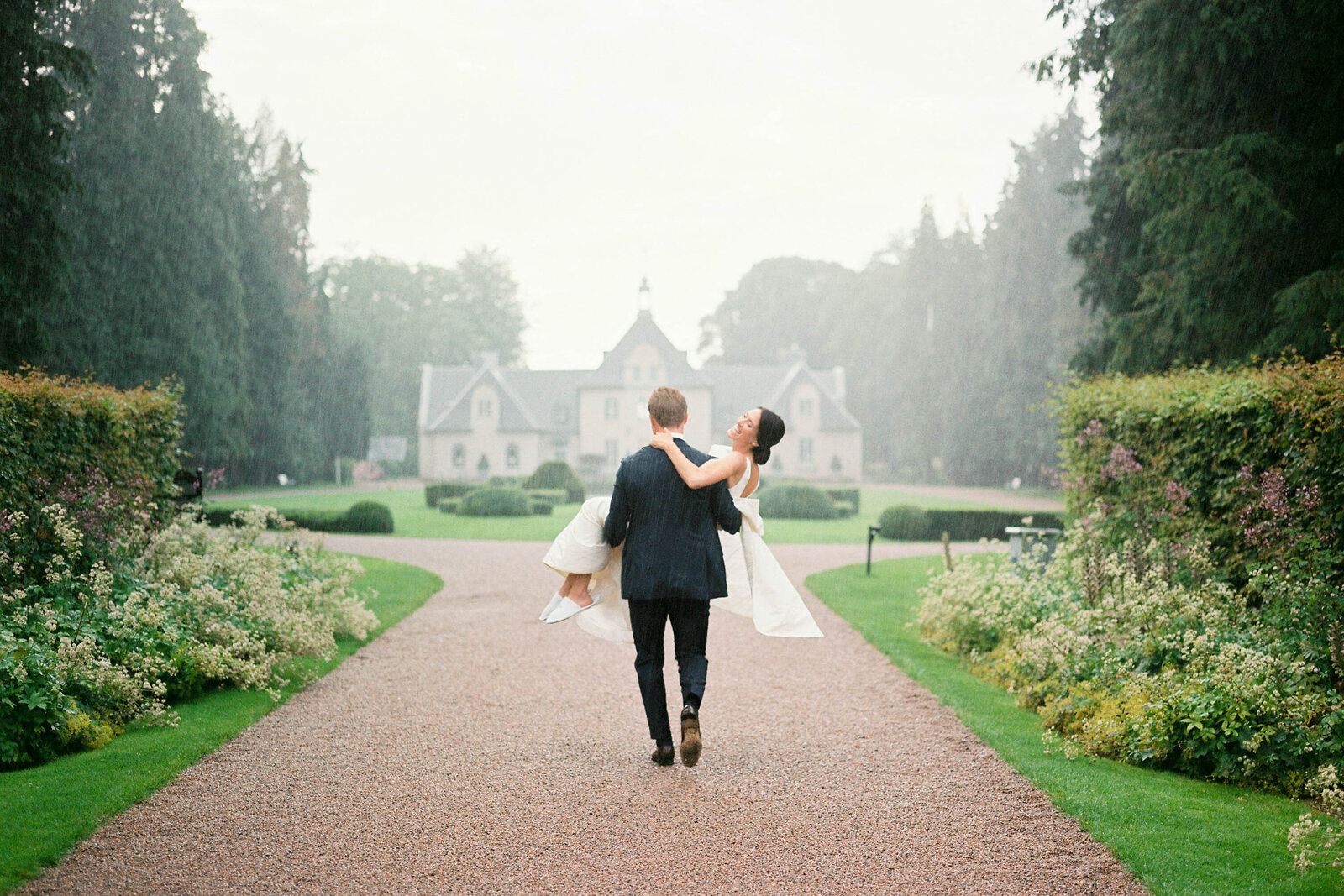 The groom carrying his bride through the rain