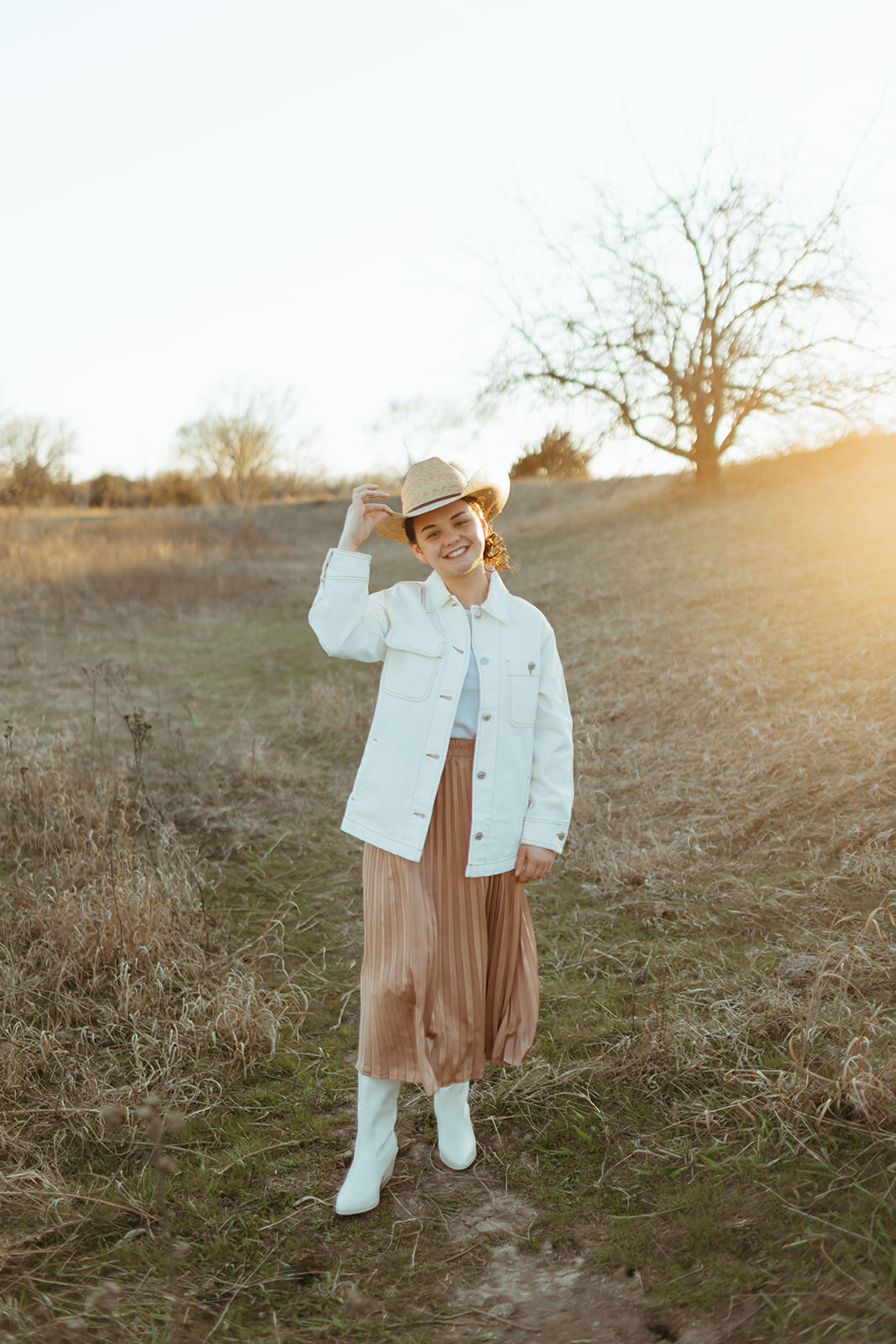 high school senior poses in a country field for senior photos with ashley cole photography