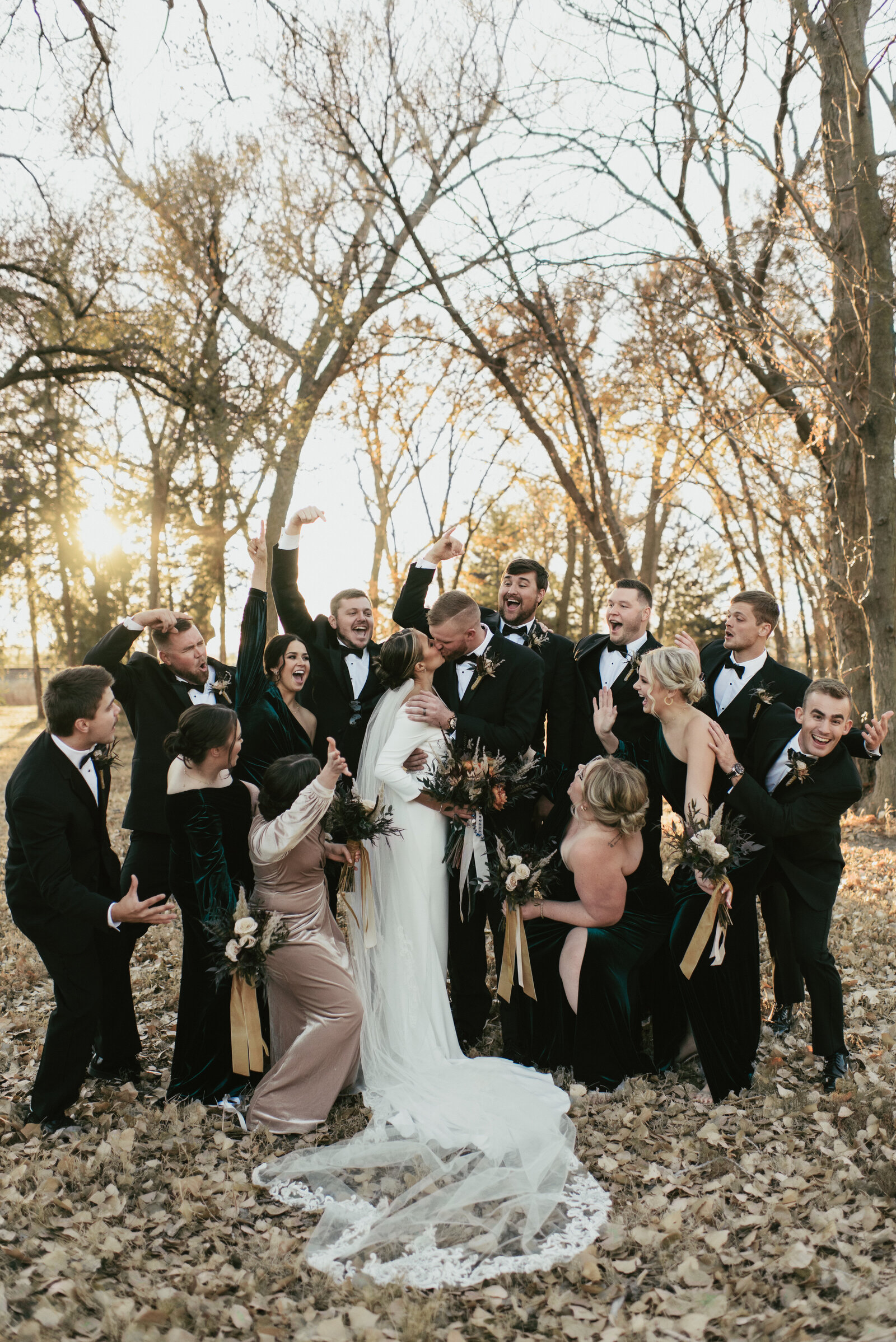 bridal party cheering while bride and groom kiss and celebrate after wedding ceremony