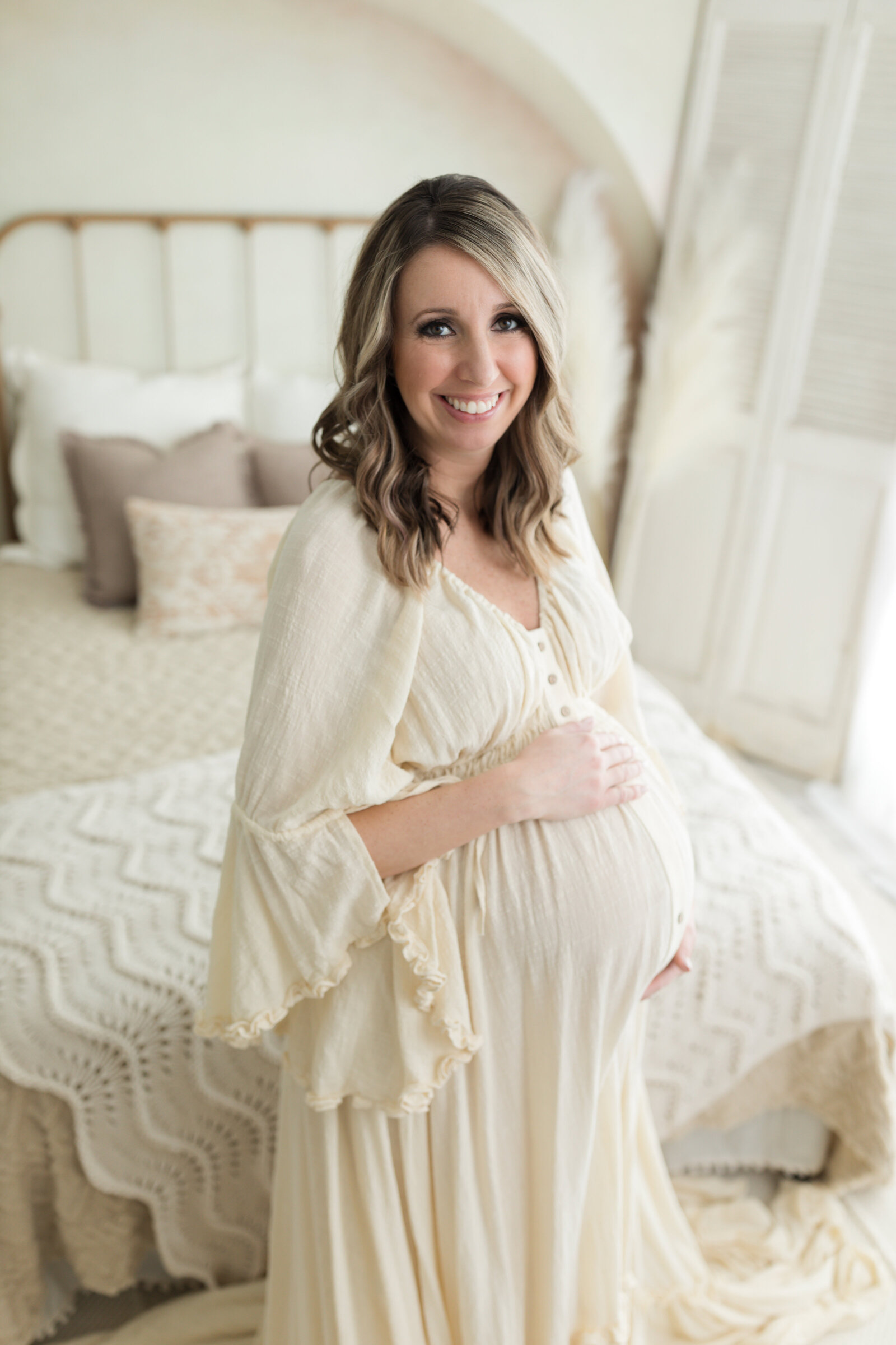 pregnant mother in cream maternity gown holding baby bump for maternity photoshoot