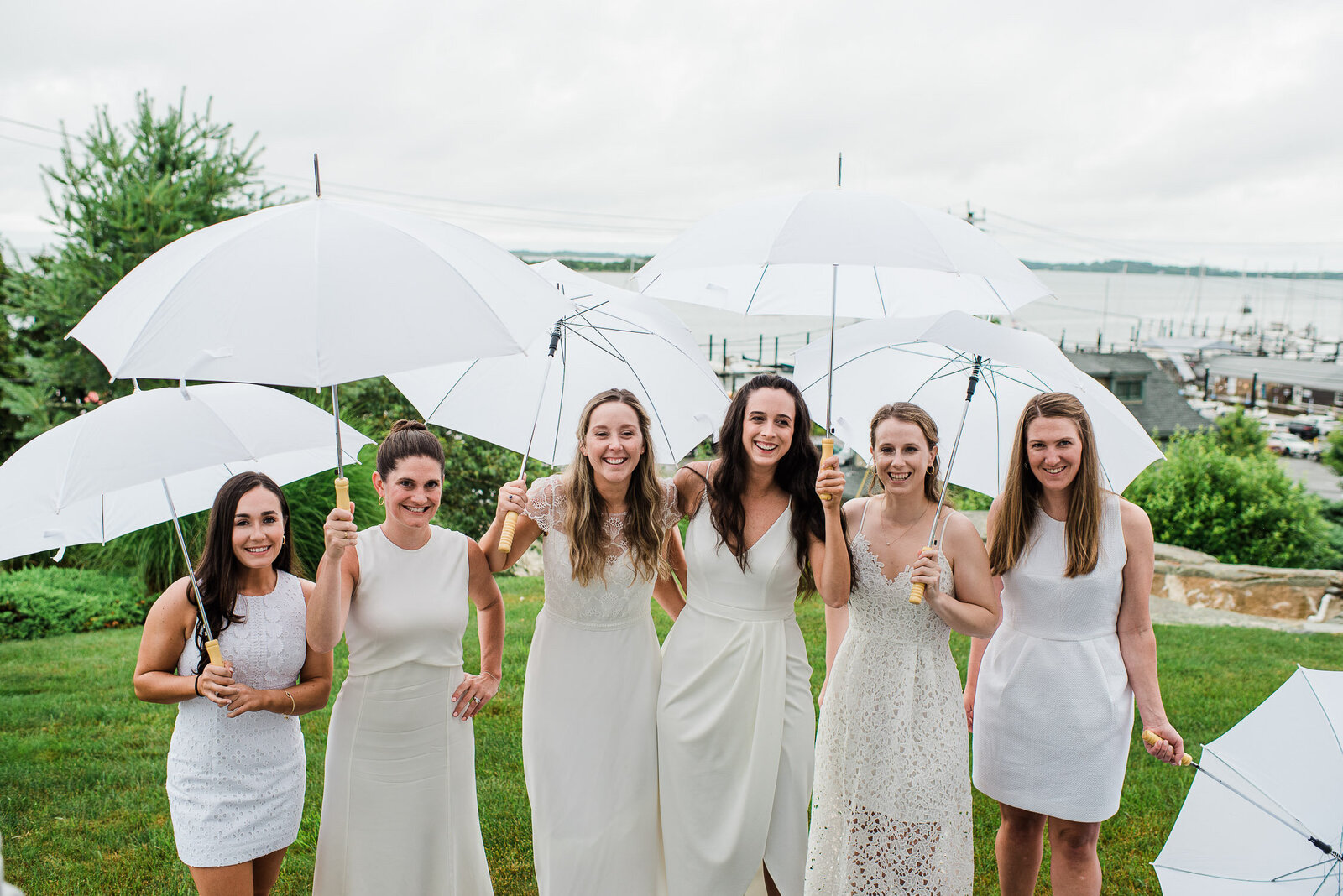 bridesmaids in white with umbrellas