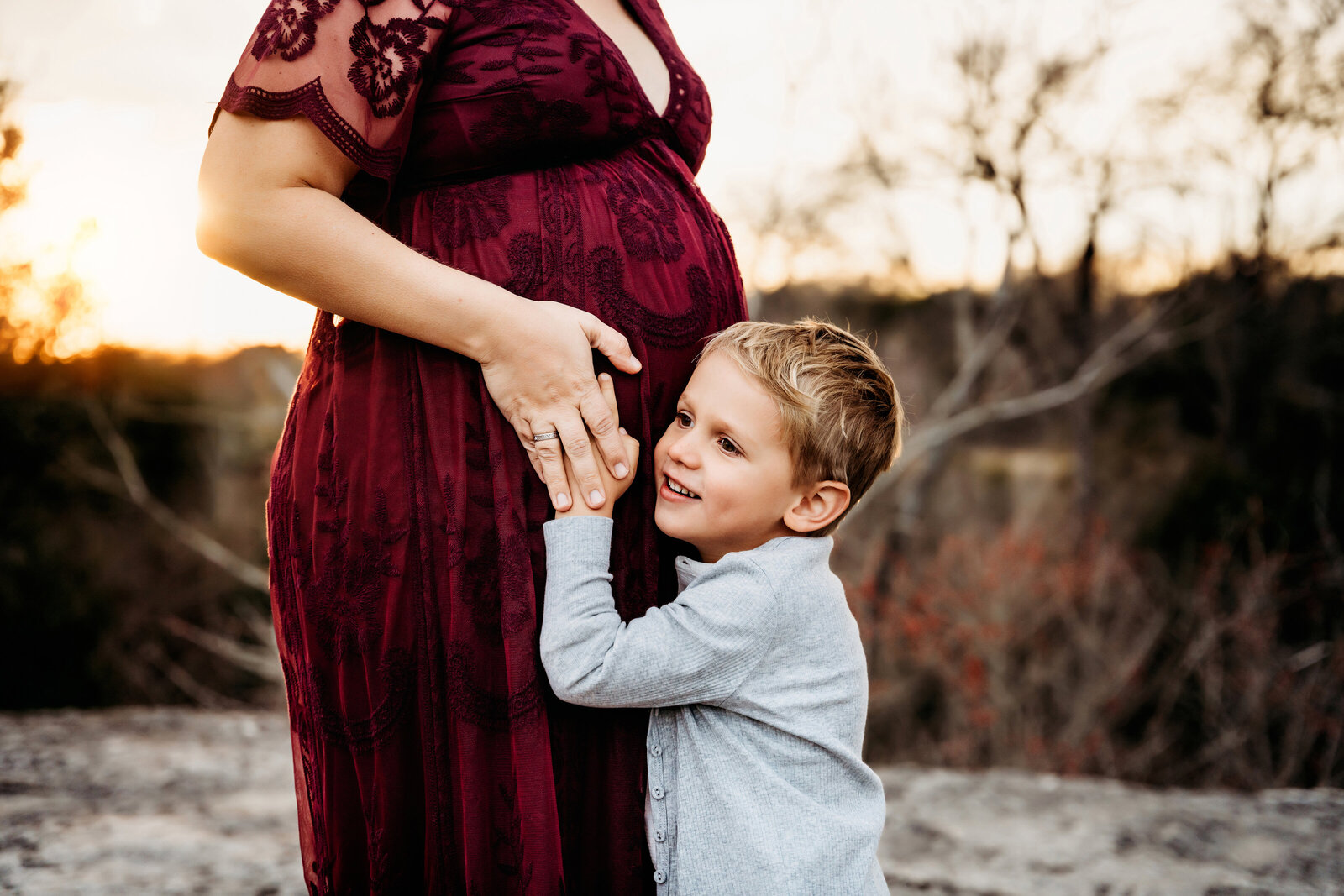 Maternity Photographer, a little boy places his face on mom's belly to listen for baby