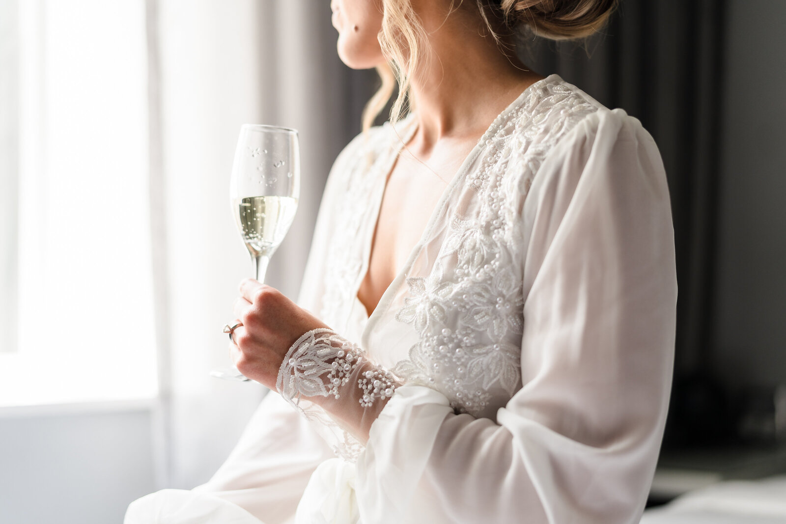 Bride holds a glass of champagne while getting ready in her suite at LeVeque Tower