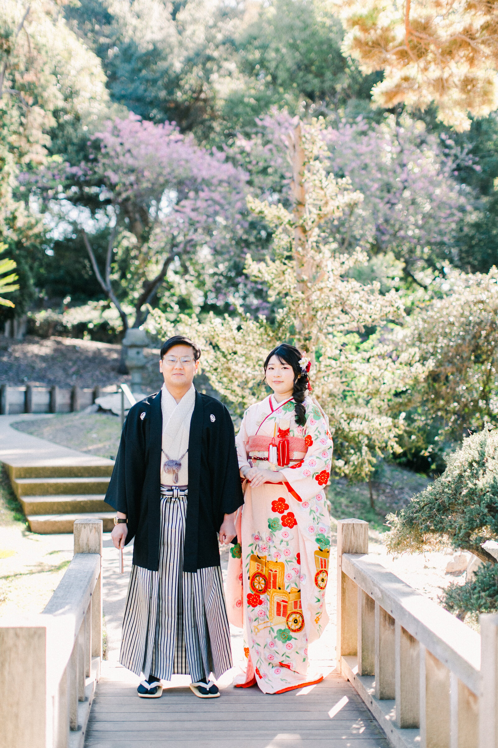 Bride in pink wedding kimono rental and groom holding hands on the wooden bridge at The Huntington Library Japanese Garden, Los Angeles California | ハンティントン図書館日本庭園 木橋で手をつなぐ着物レンタルウェディングカップル