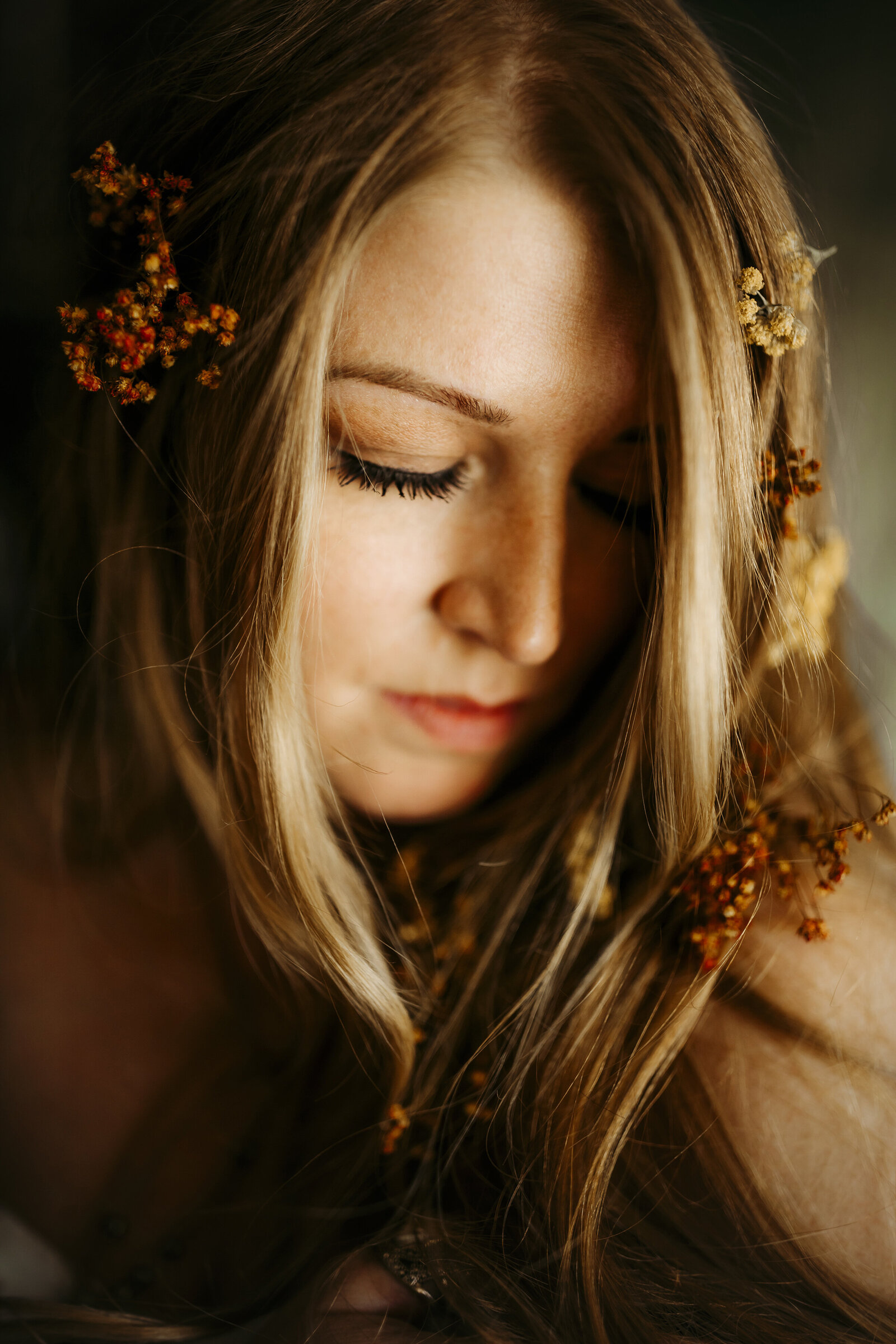 red headed woman poses with flowers in her hair for portraits