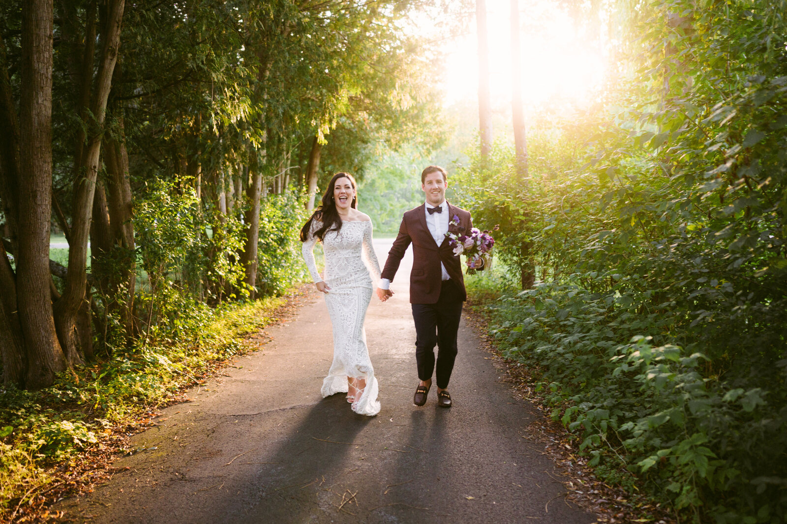 Mountainnaire Gatherings Photo of Happy Couple walking along tree lined driveway Vermont Wedding Planner