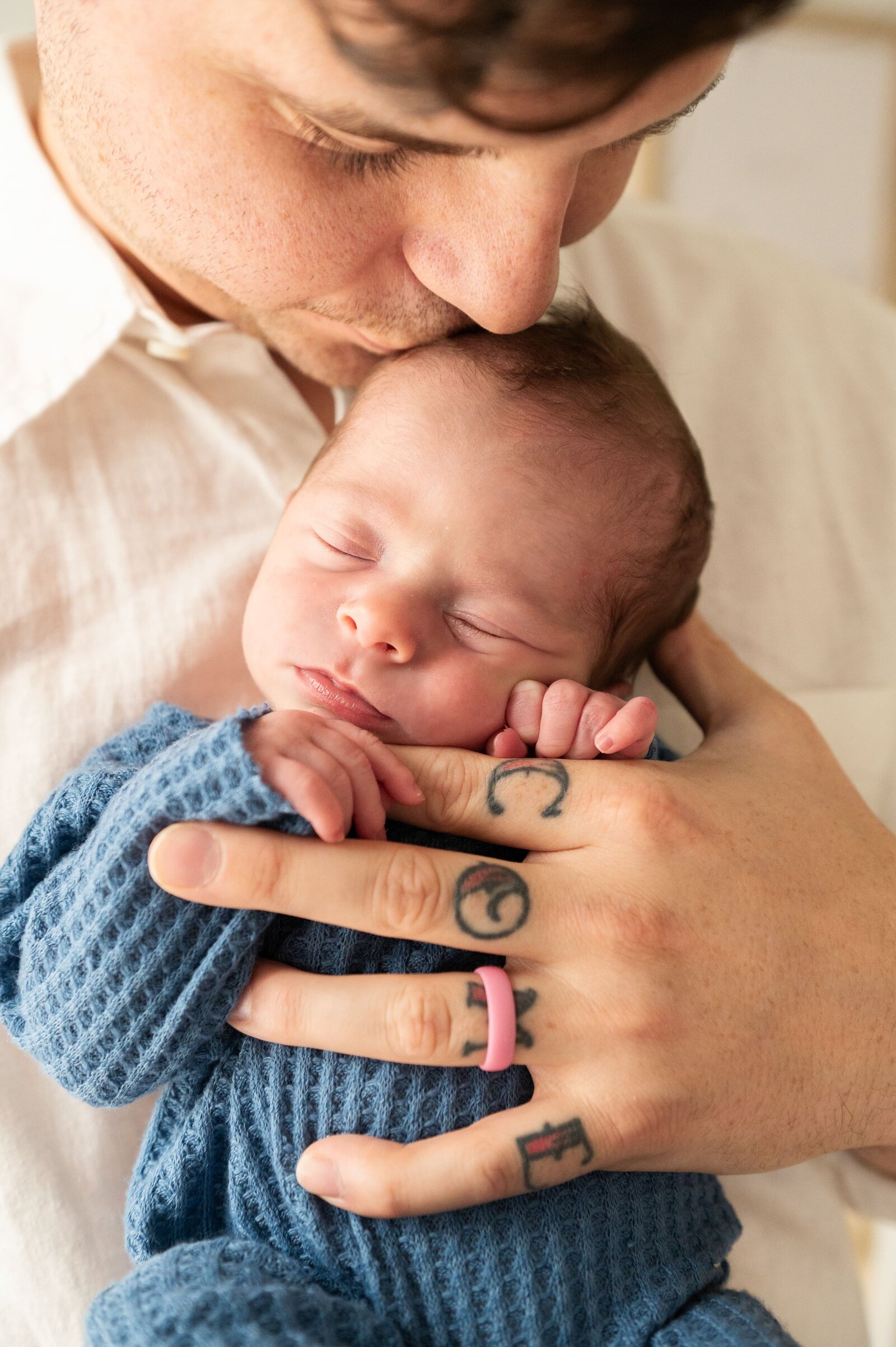 dad with attoos holding his newborn sleeping son