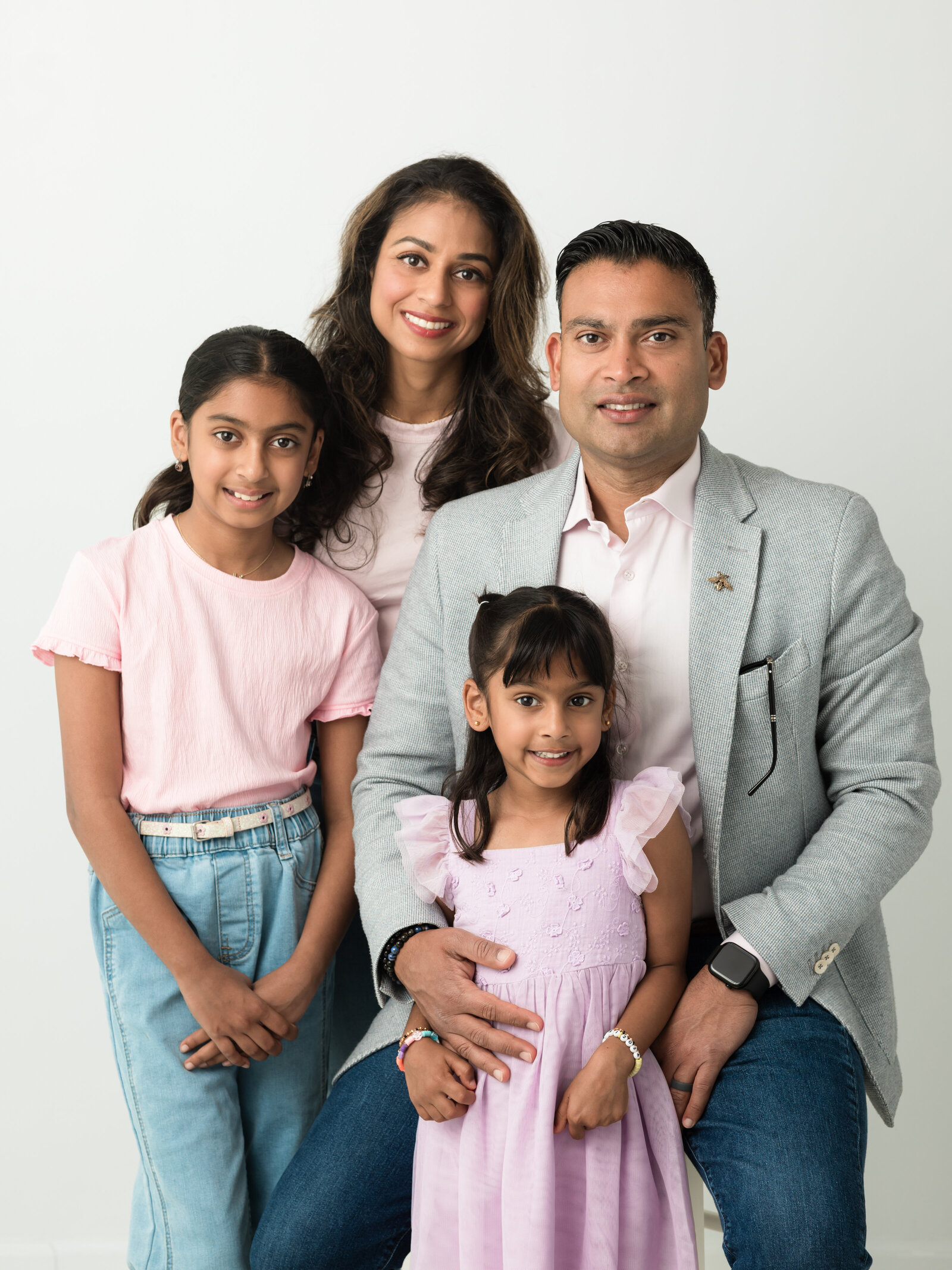 parents and two daughters posed for white studio portrait