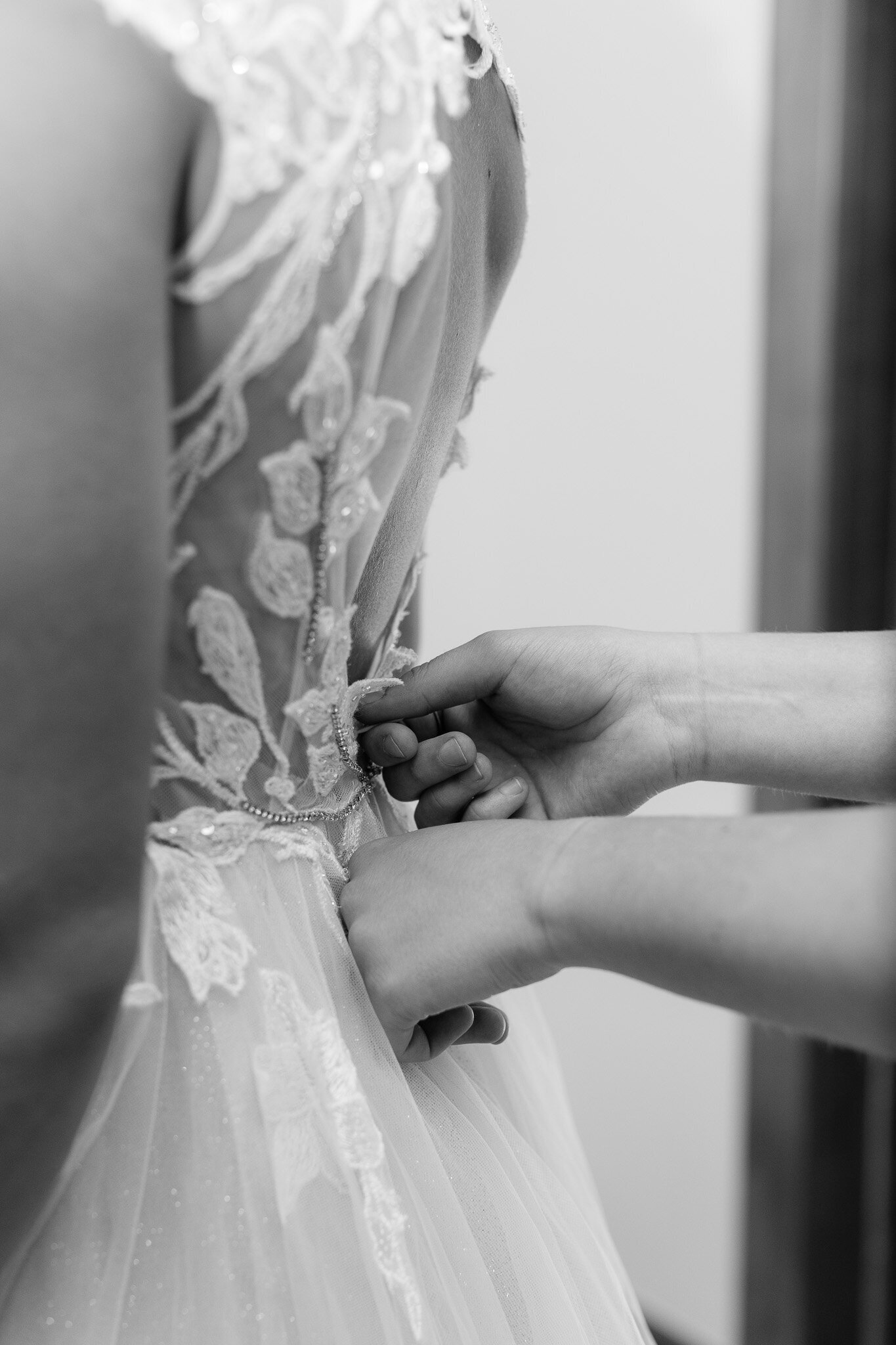 Maid of honor helping bride zip back of dress in black and white