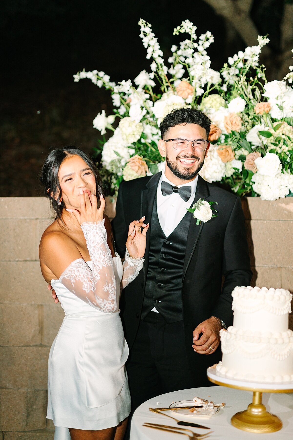 Bride and groom smiling and eating cake at their wedding reception photographed by Sherr Weddings, married photo and videography team in San Diego, California.