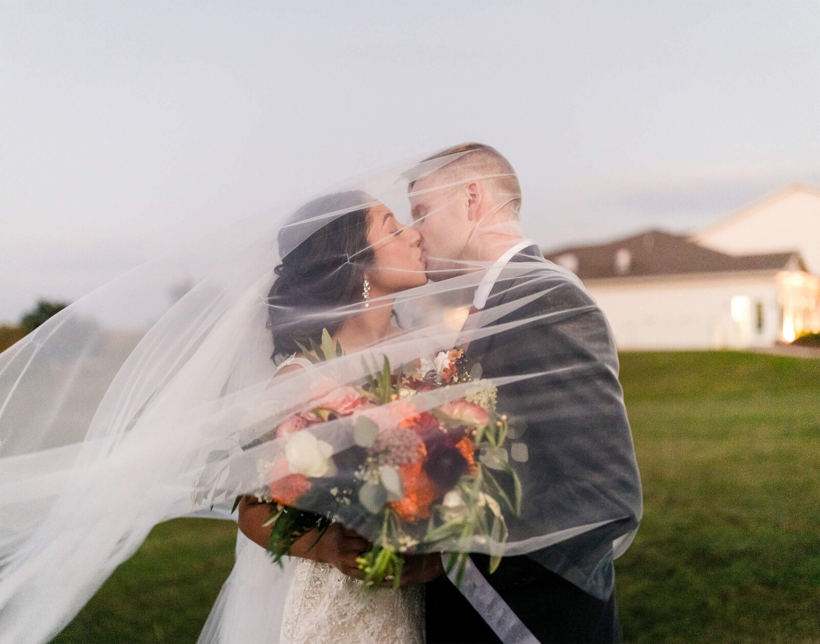 Bride and Groom kissing  with her veil being flown by the wind.