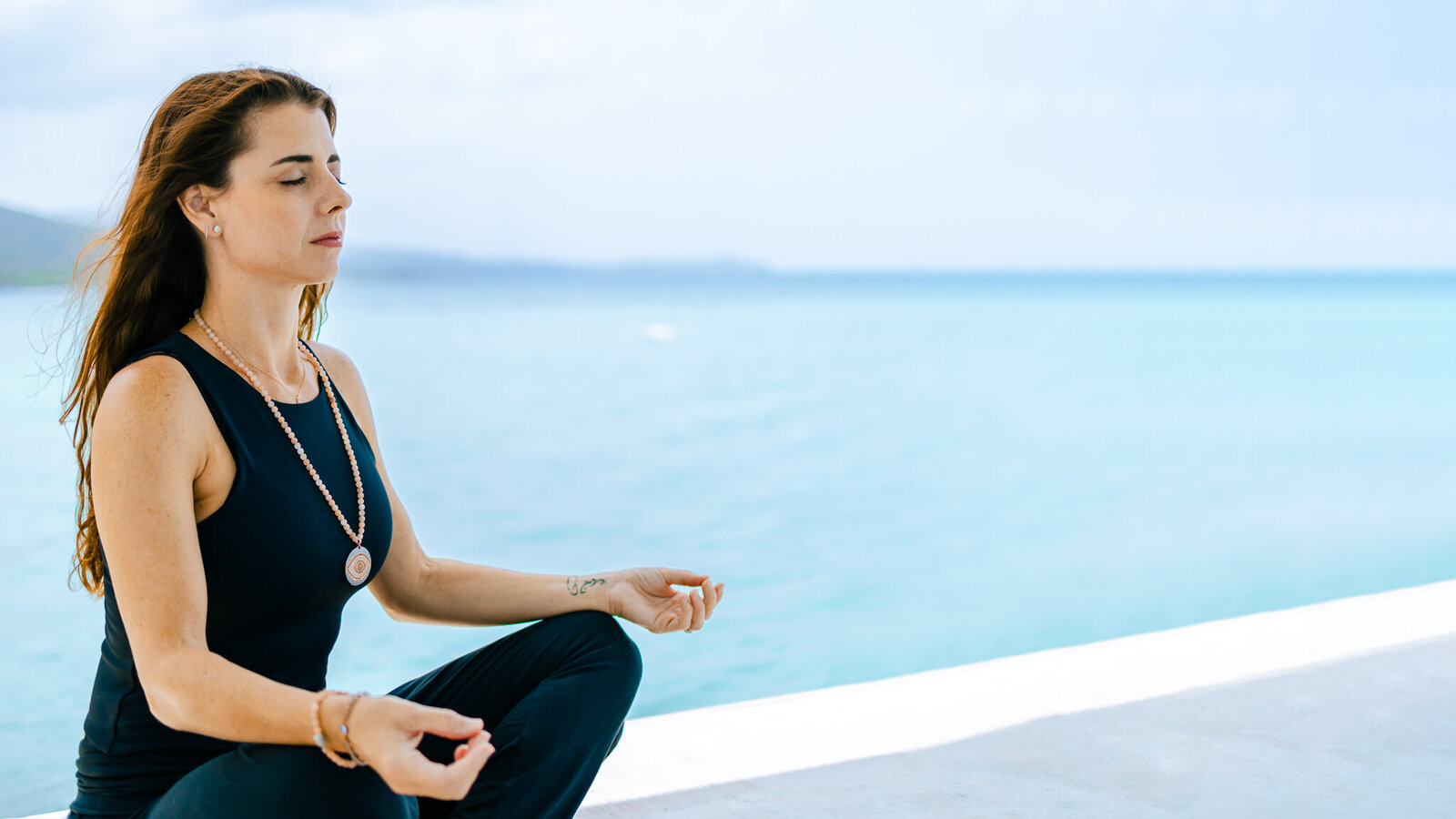 Woman working on mindset and meditating near the ocean