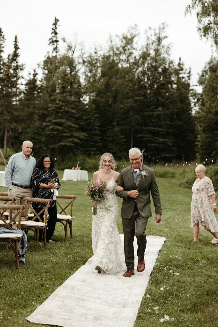 Father and bride walking down the aisle smiling