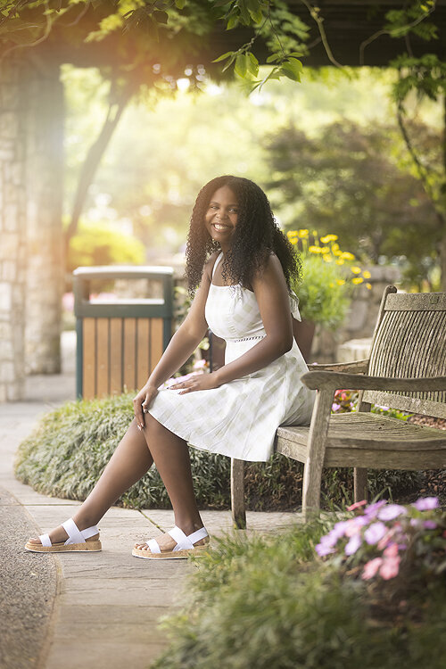 Senior girl sits on bench at Dallas Arboretum