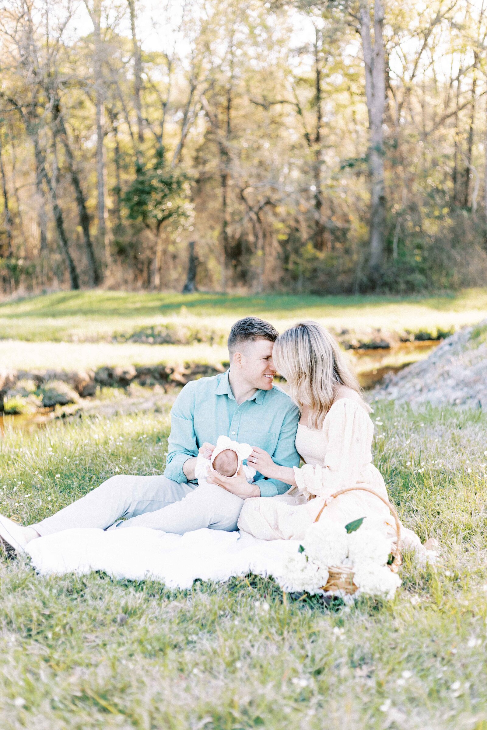 parents sitting on blanket outside with newborn in baby photos in peoria illinois