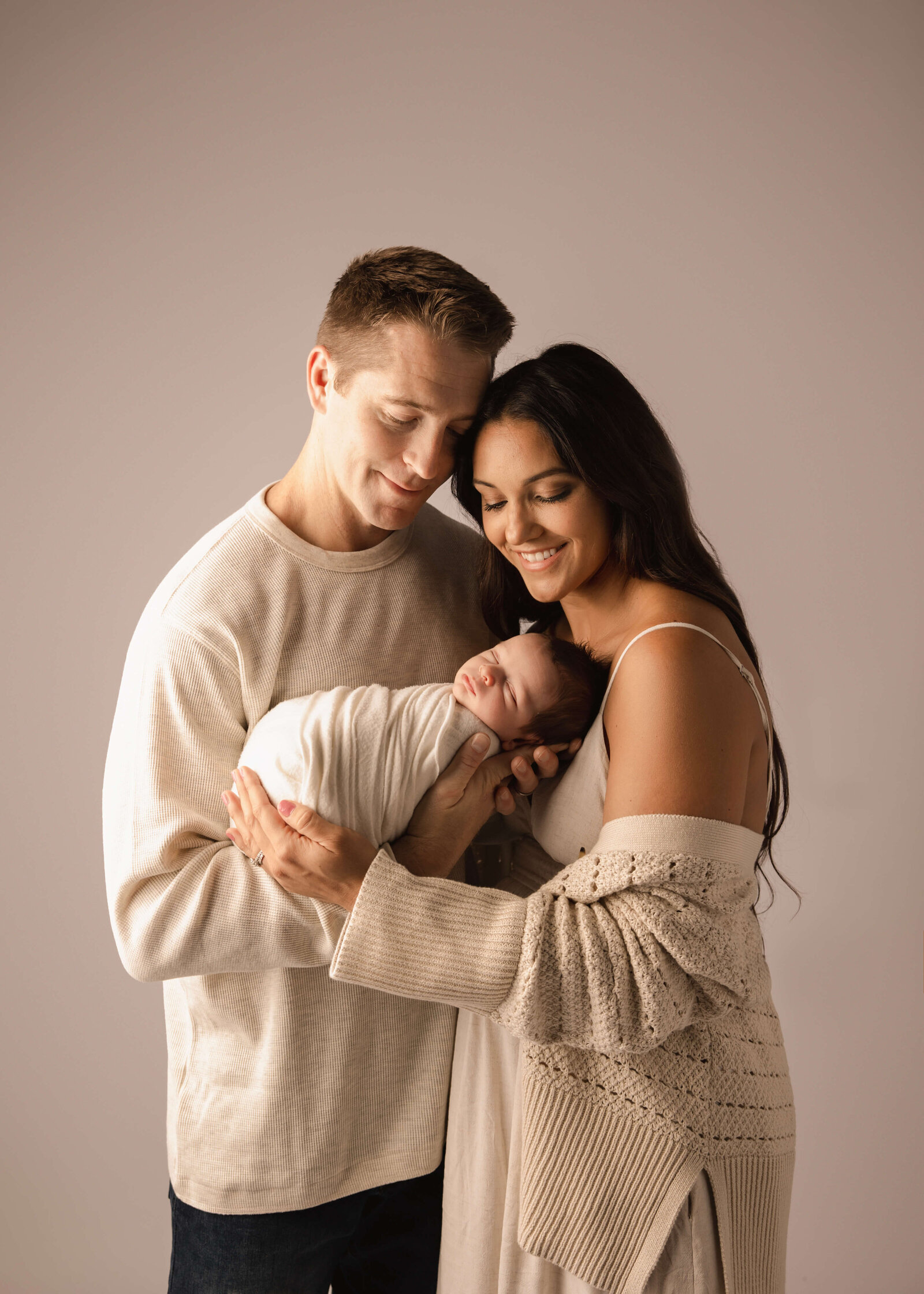 Couple posing with their new baby  in studio by Ashley Nicole Photography