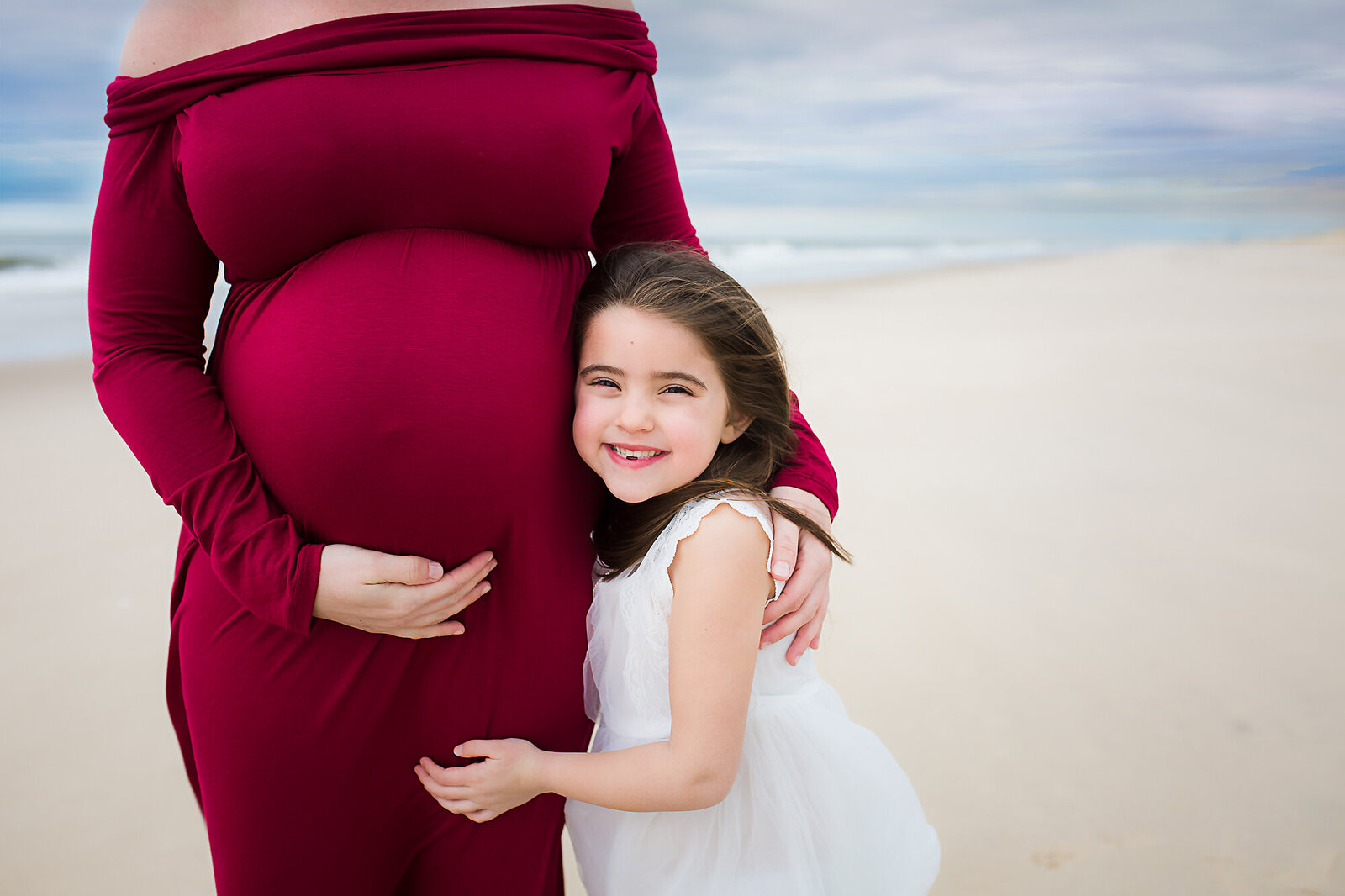 little girl posing with mom's pregnant belly by PHILADELPHIA MATERNITY PHOTOGRAPHER