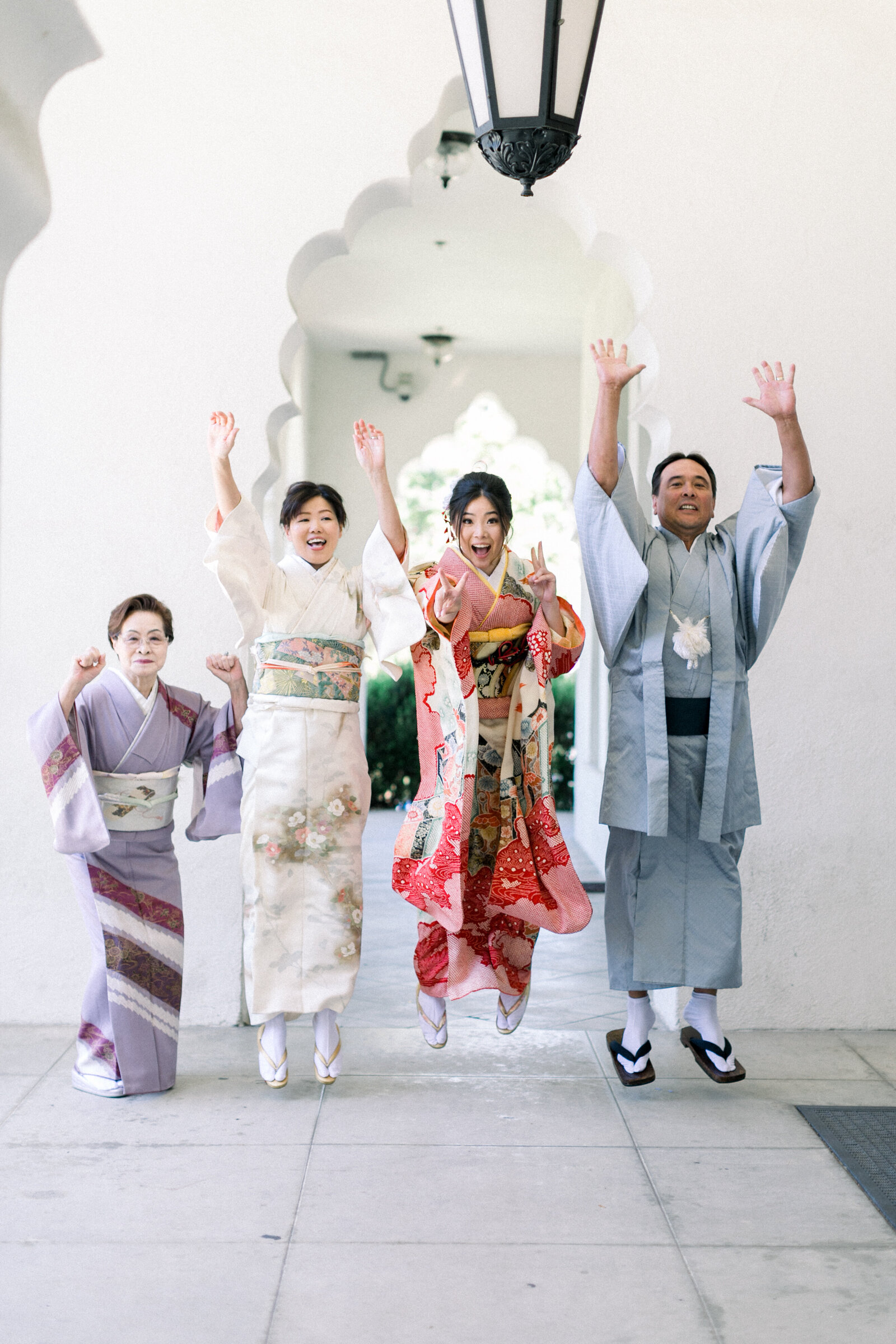 Family celebrating Seijinshiki (coming-of-age) at Brand Park Glendale, jumping with joy in colorful kimono and hakama, kimono rental Los Angeles | ロサンゼルス・ブランドパークでの成人式、振袖や袴姿の家族が元気にジャンプしてお祝い