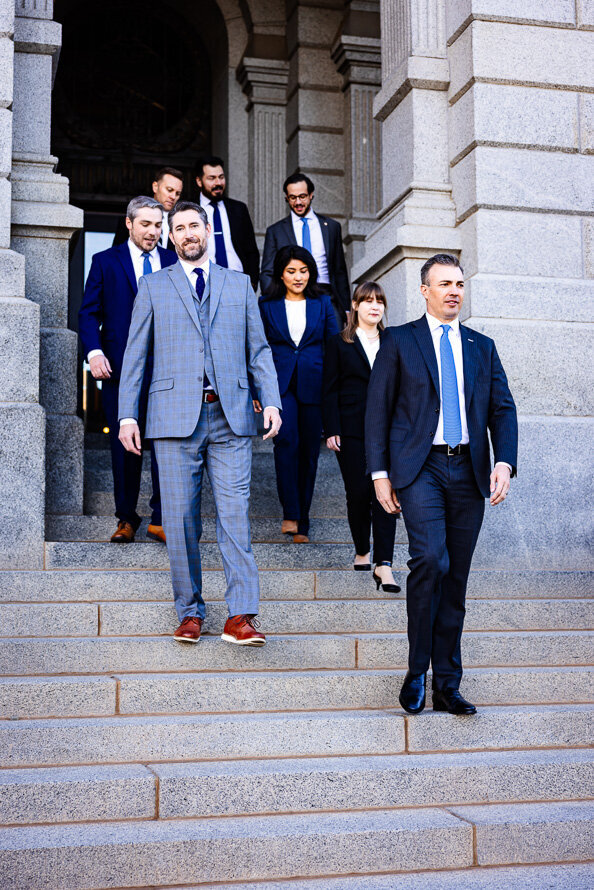 Group of lawyers walks down the stairs at the Colorado State Capitol as a part of their branding session.