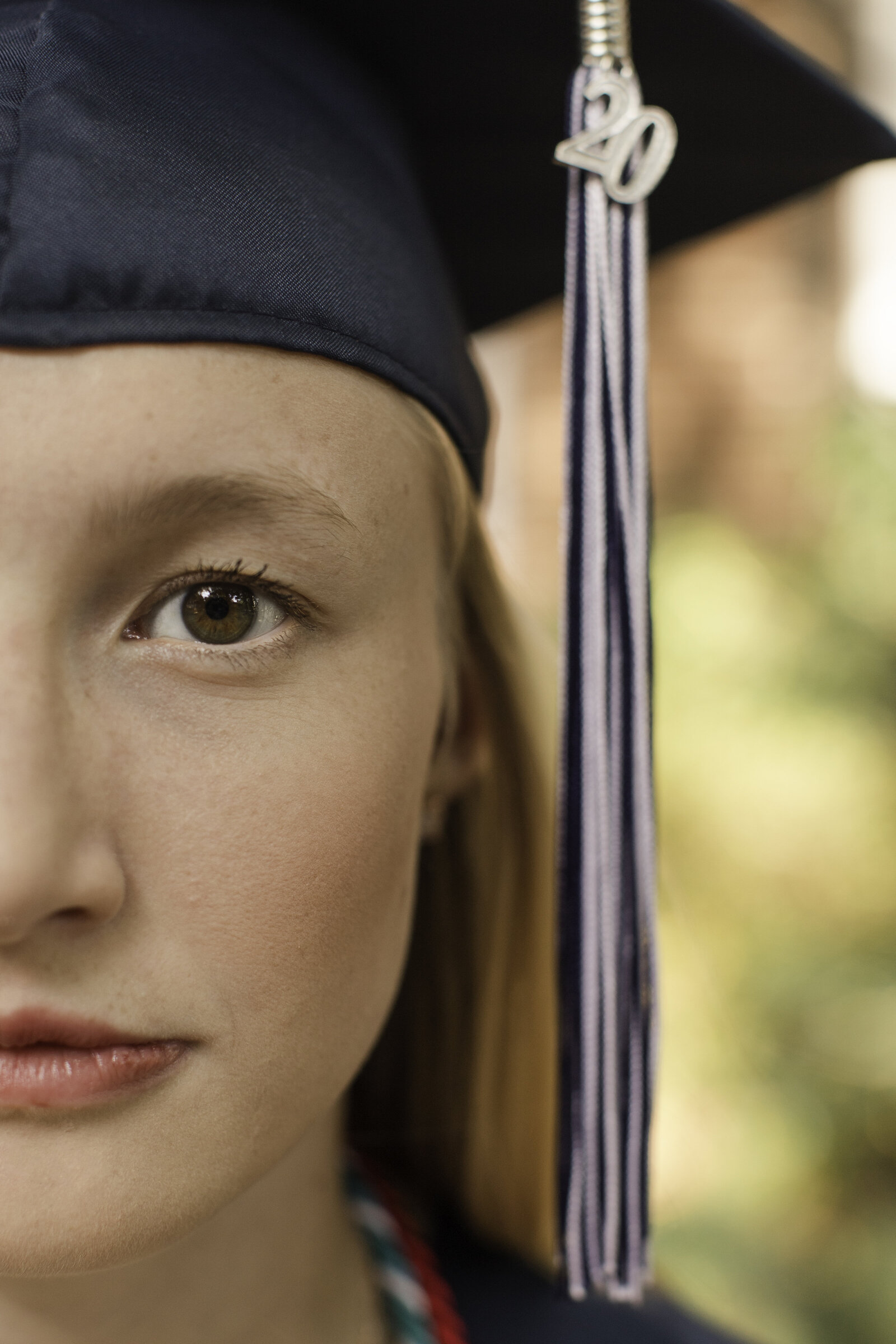 close up of half of a girls face in a cap with tassel