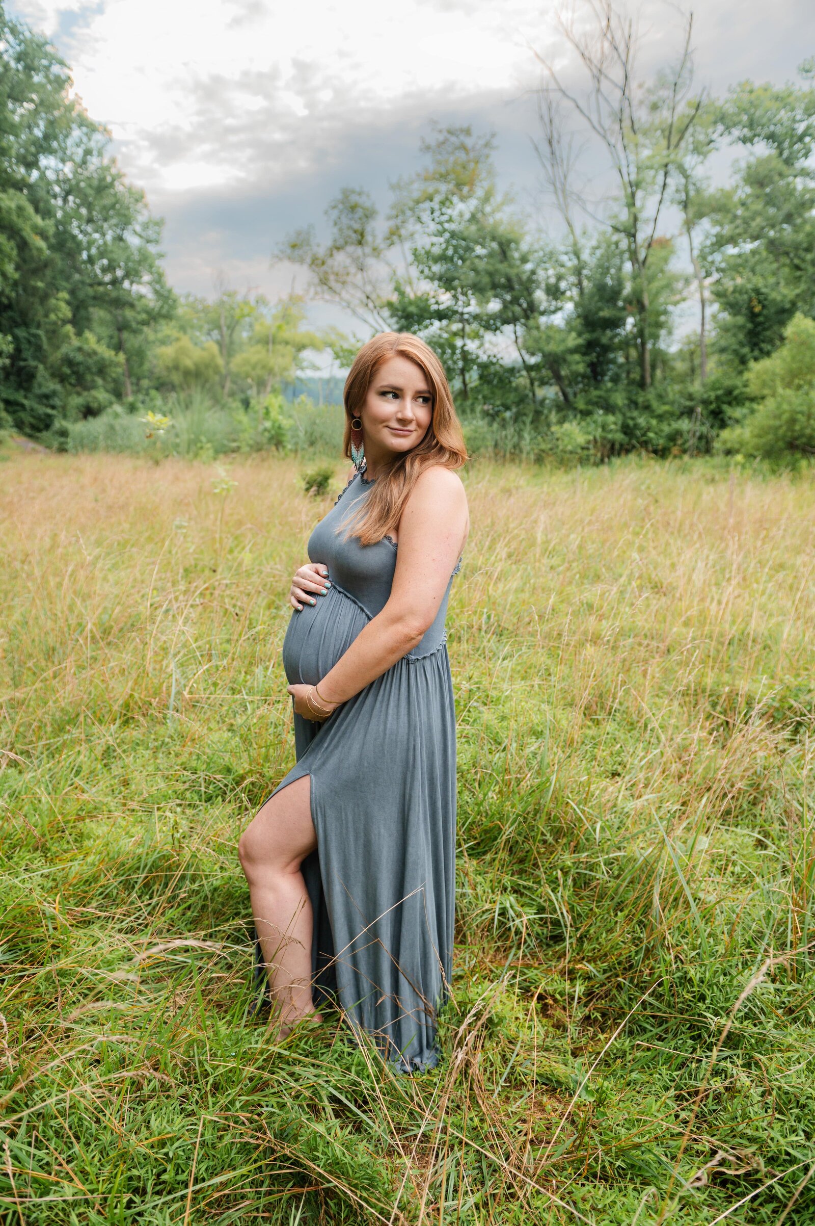 woman in blue dress holding her pregnant belly