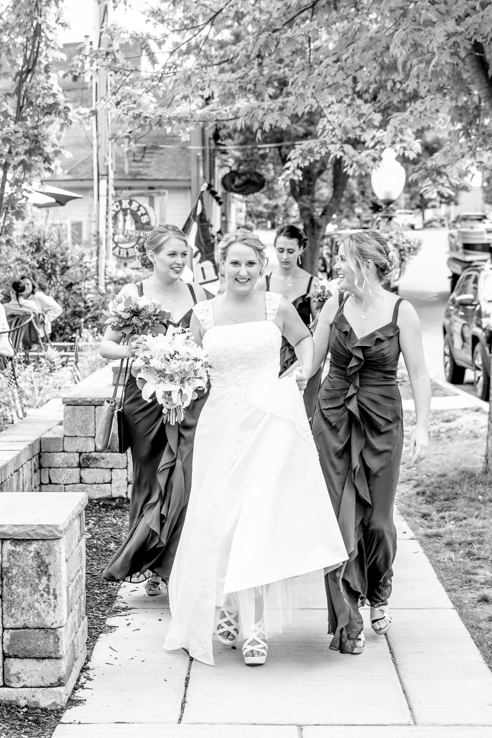 Black and white photo of a bridal party walking down the sidewalk.