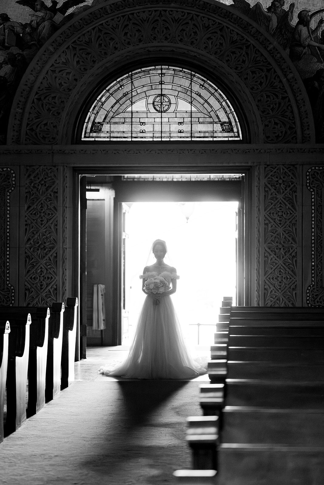 The silhouette of the bride is framed beautifully at the entrance of Stanford Memorial Church, highlighting the grandeur and serenity of the venue.