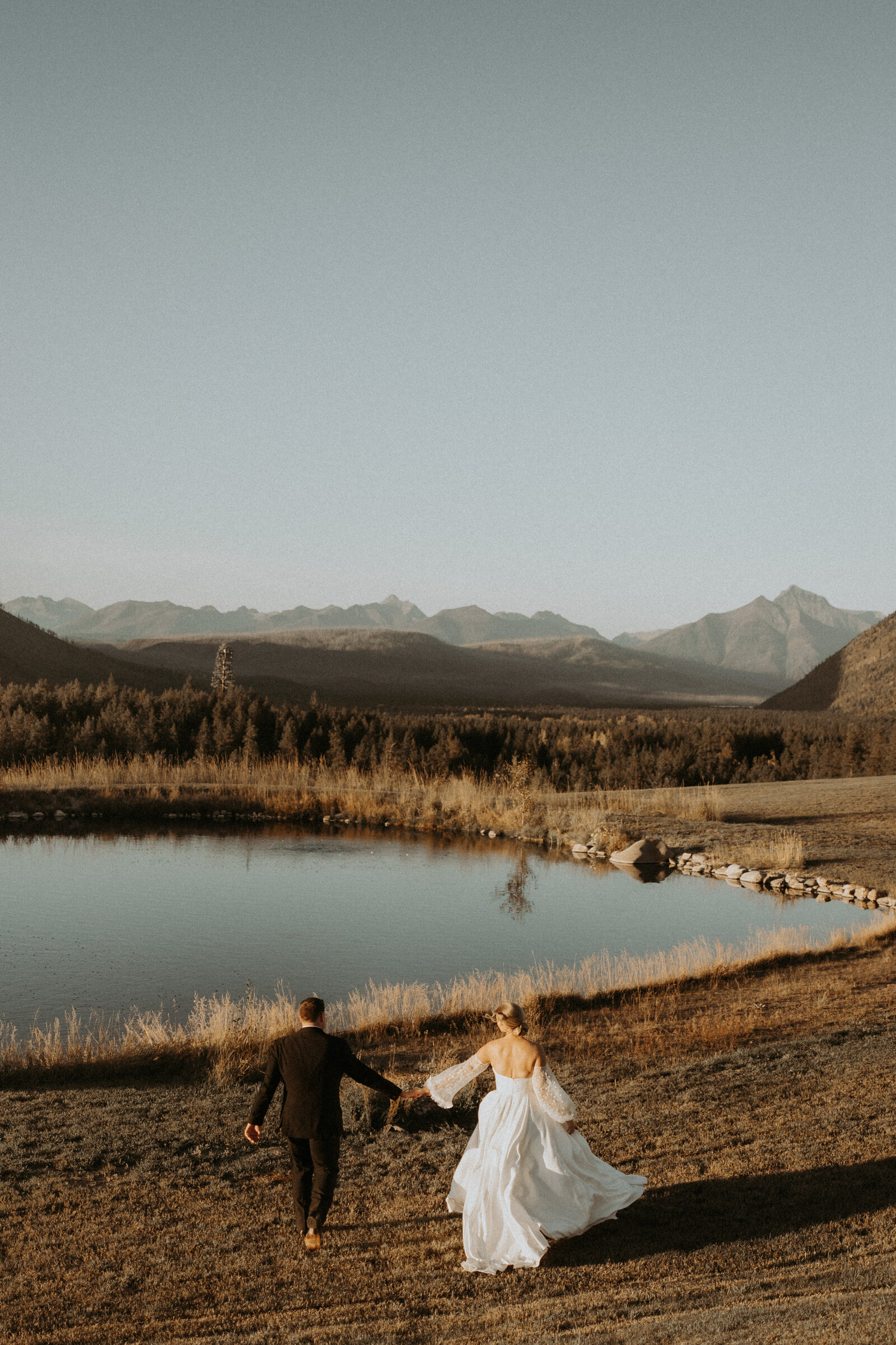 couple running while holding hands in an open field 