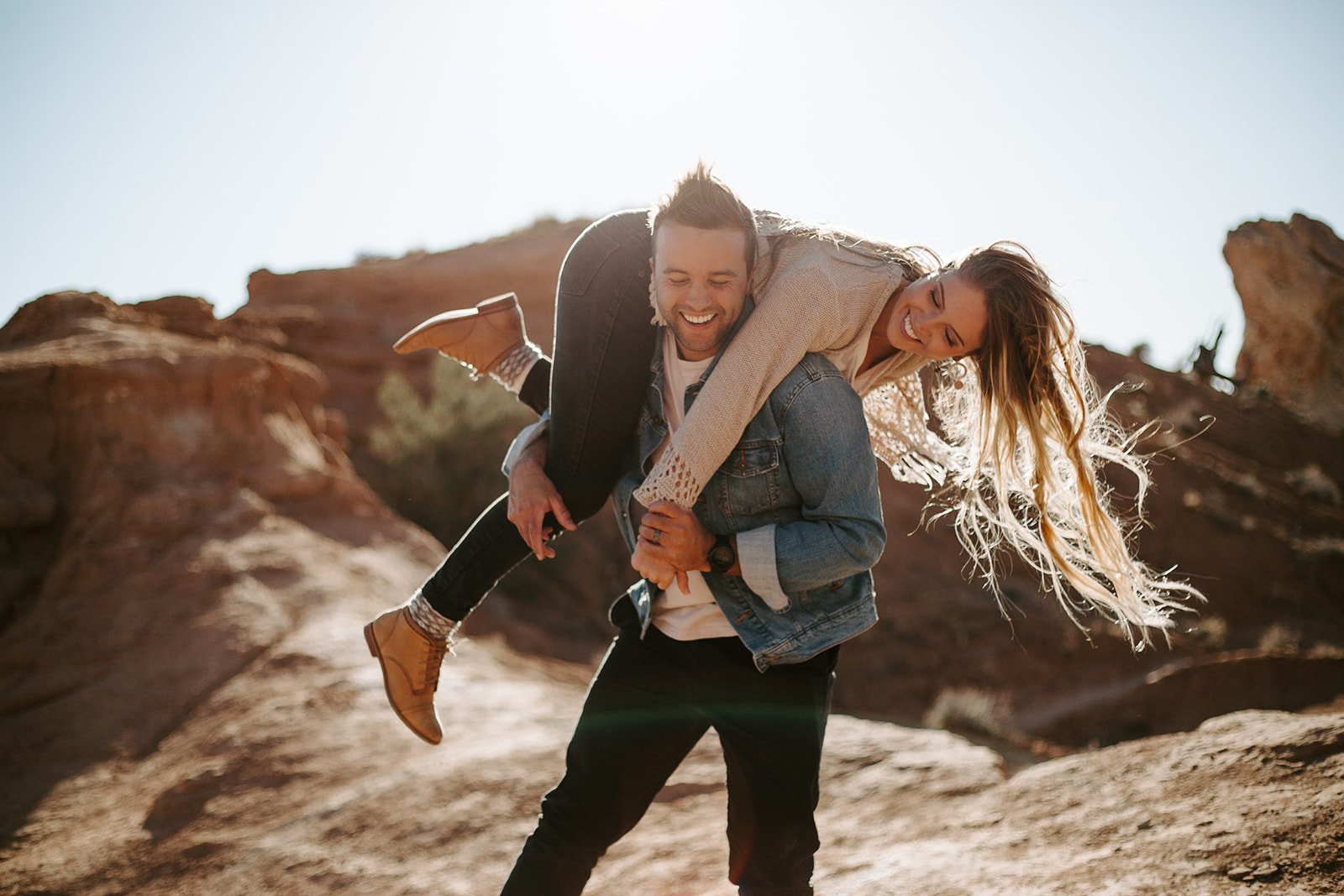 Man holding his girlfriend over his shoulders laughing together during their Arizona engagement session