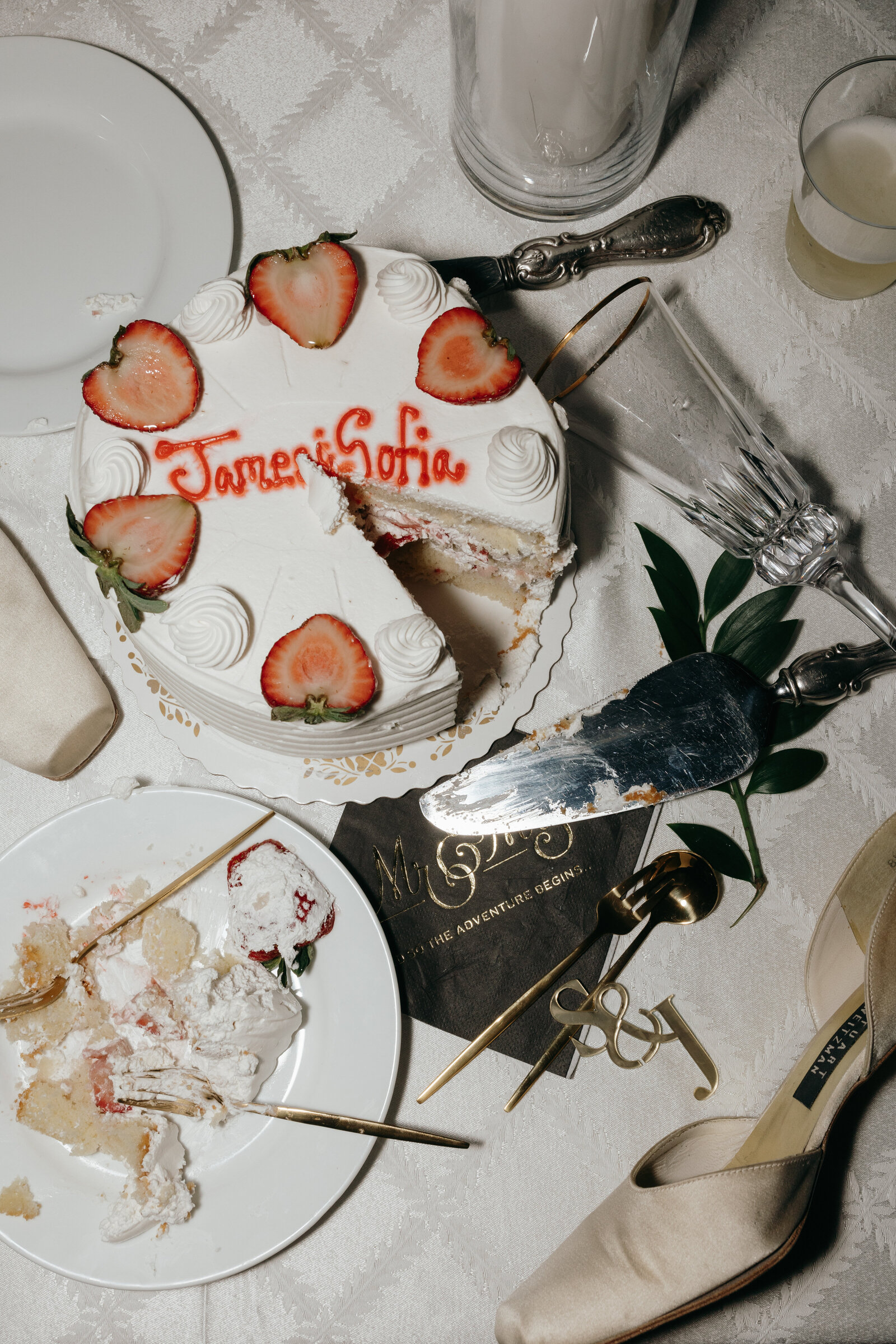 Small wedding cake topped with strawberries cut by the groom and bride in a flatlay | Emma LeeAnn Photography