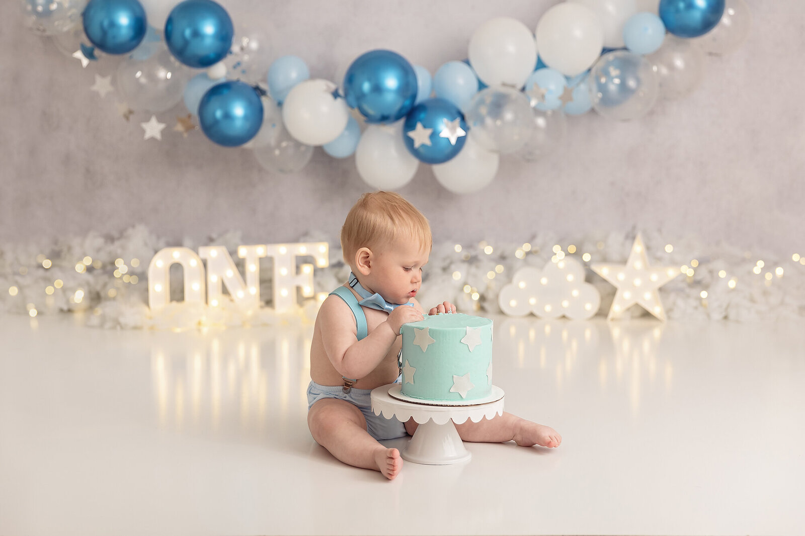 baby eating teal cake with white stars by milestone photographer new philadelphia