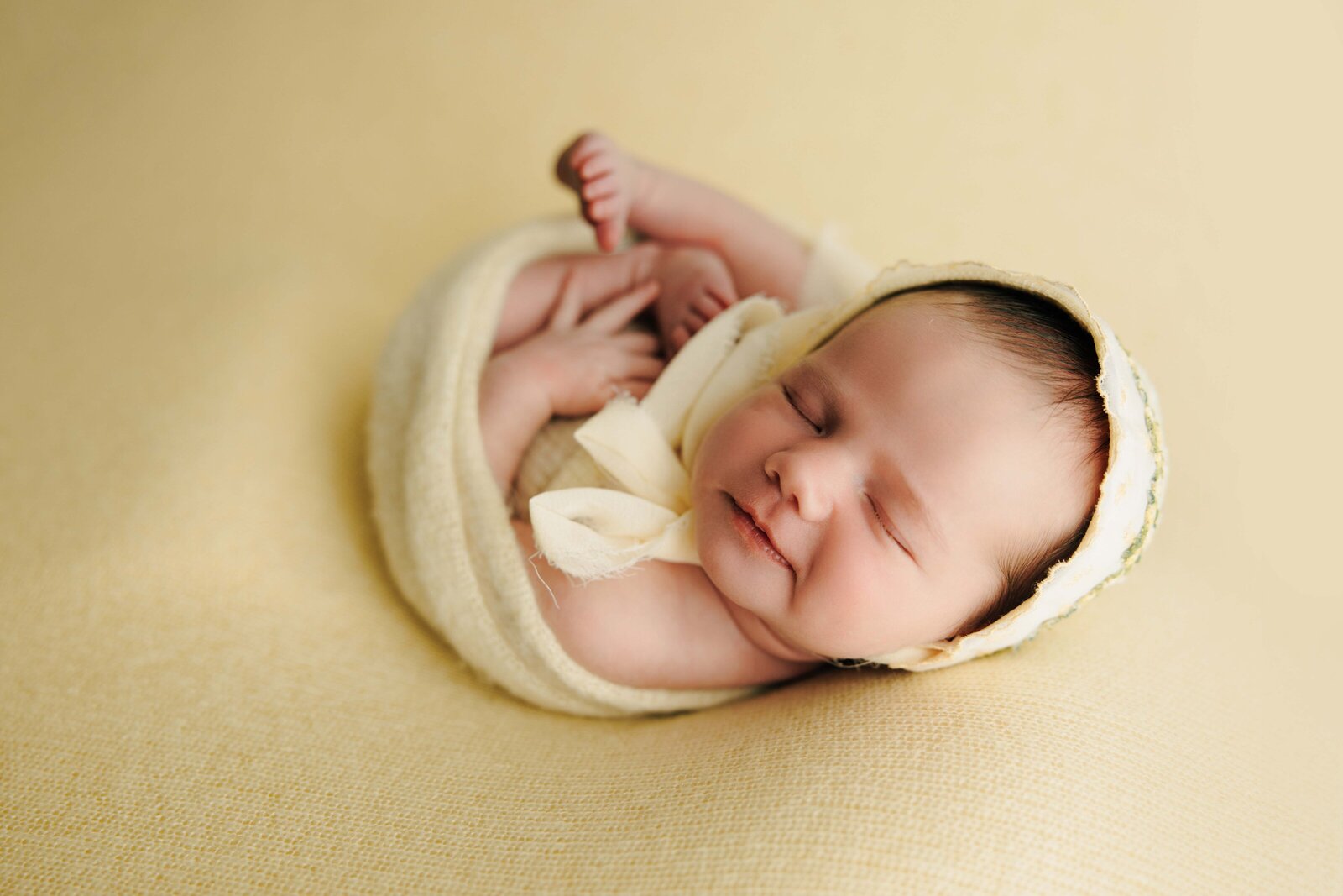baby girl smiles on yellow backdrop