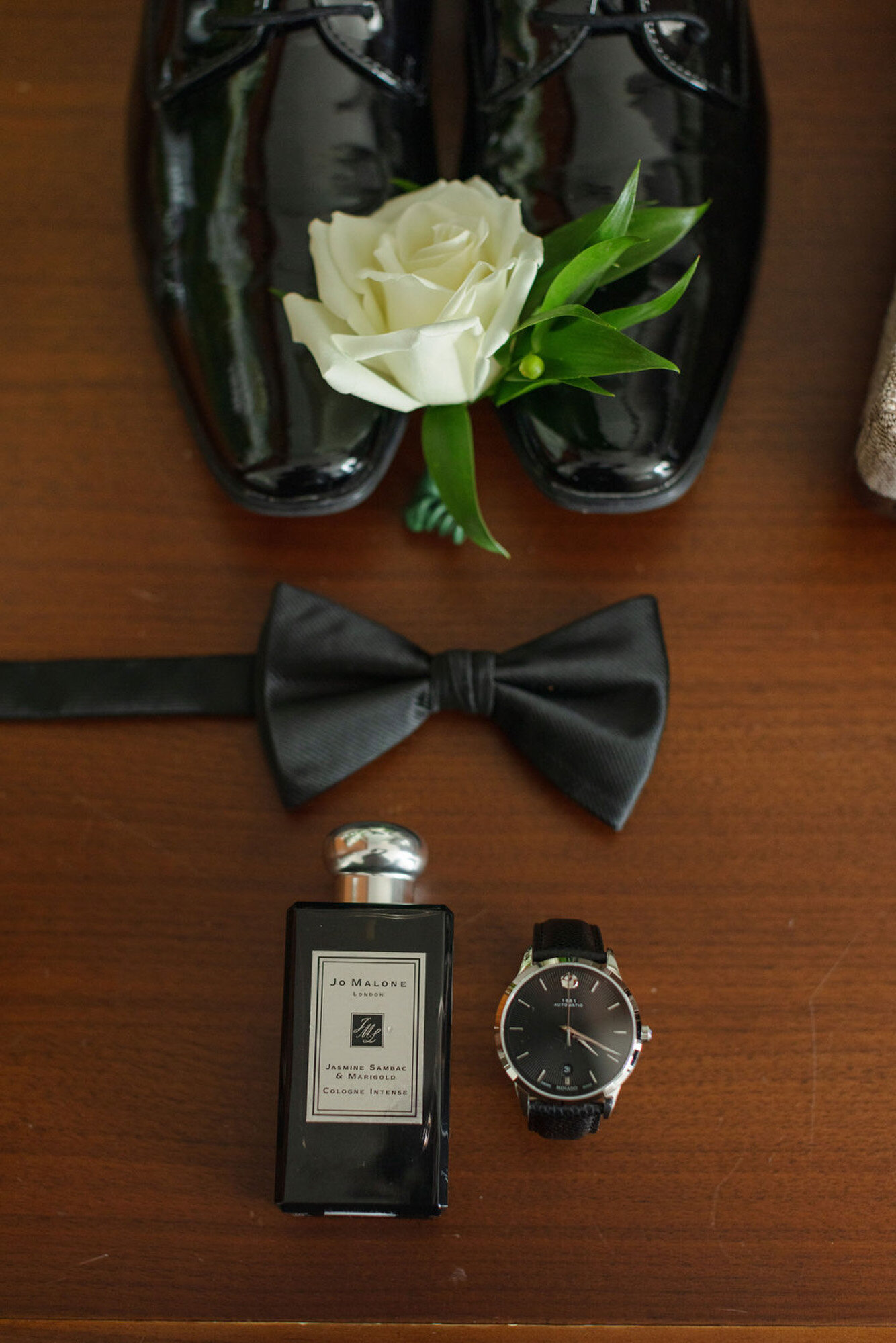 groom's shoes with bow tie, cologne, and watch