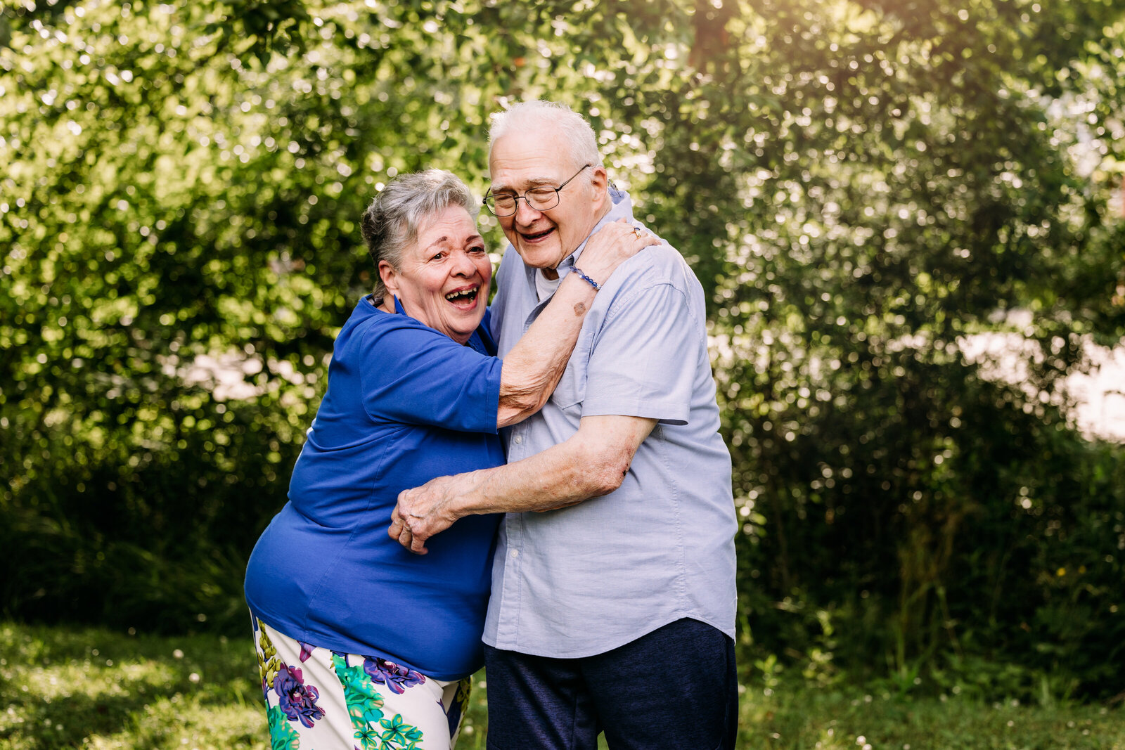 An elderly couple hold each other close while laughing together