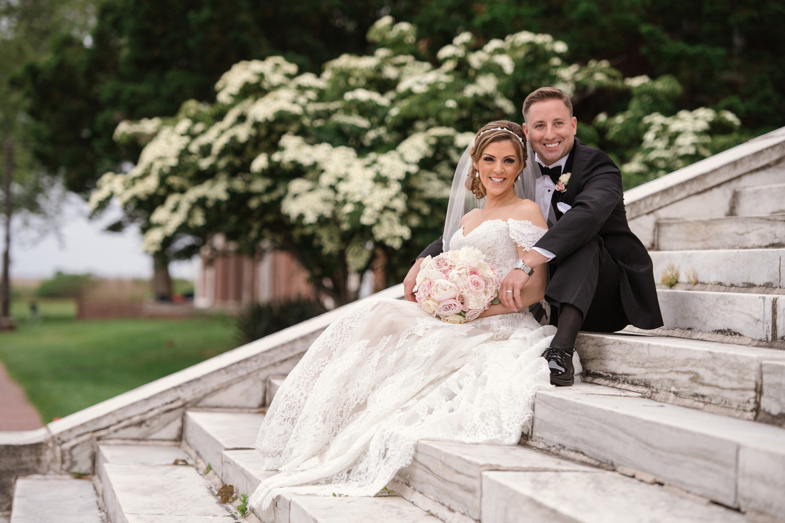 Bride and groom sitting at the steps of the Bourne Mansion