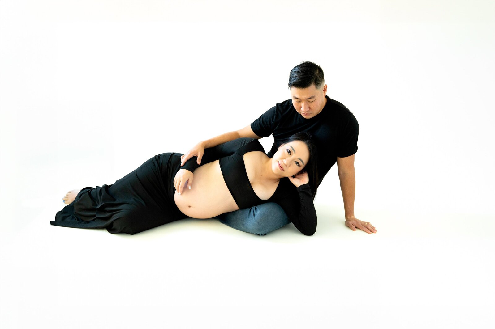 maternity photography session with a pregnant woman laying on her side in her husbands lap