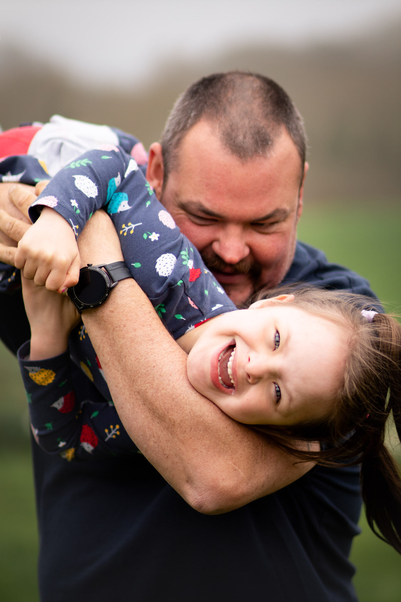 Little girl plays with her dad during family photography session in Devon