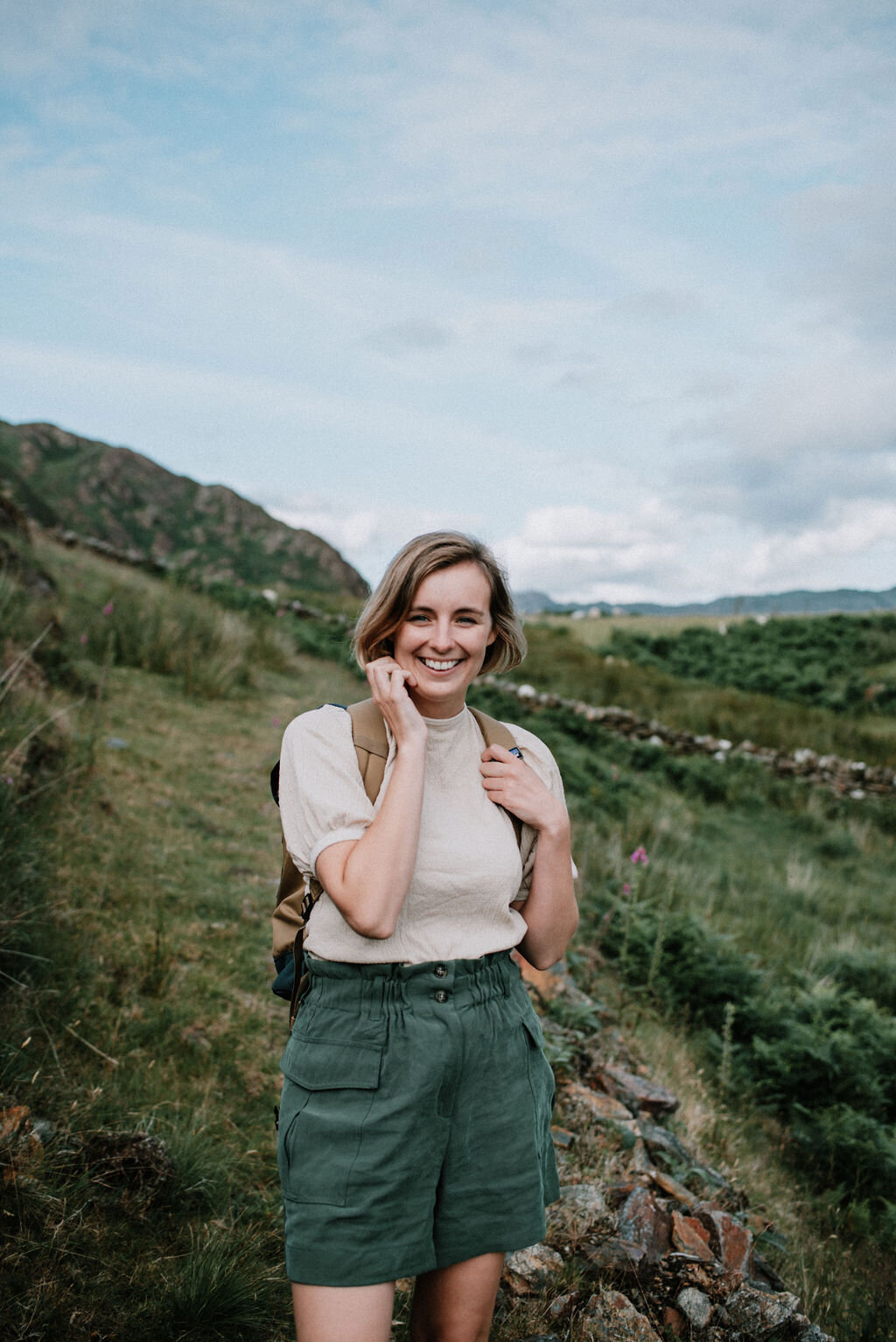 woman with a backpack and green shorts is hiking a mountain in snowdonia in the summer
