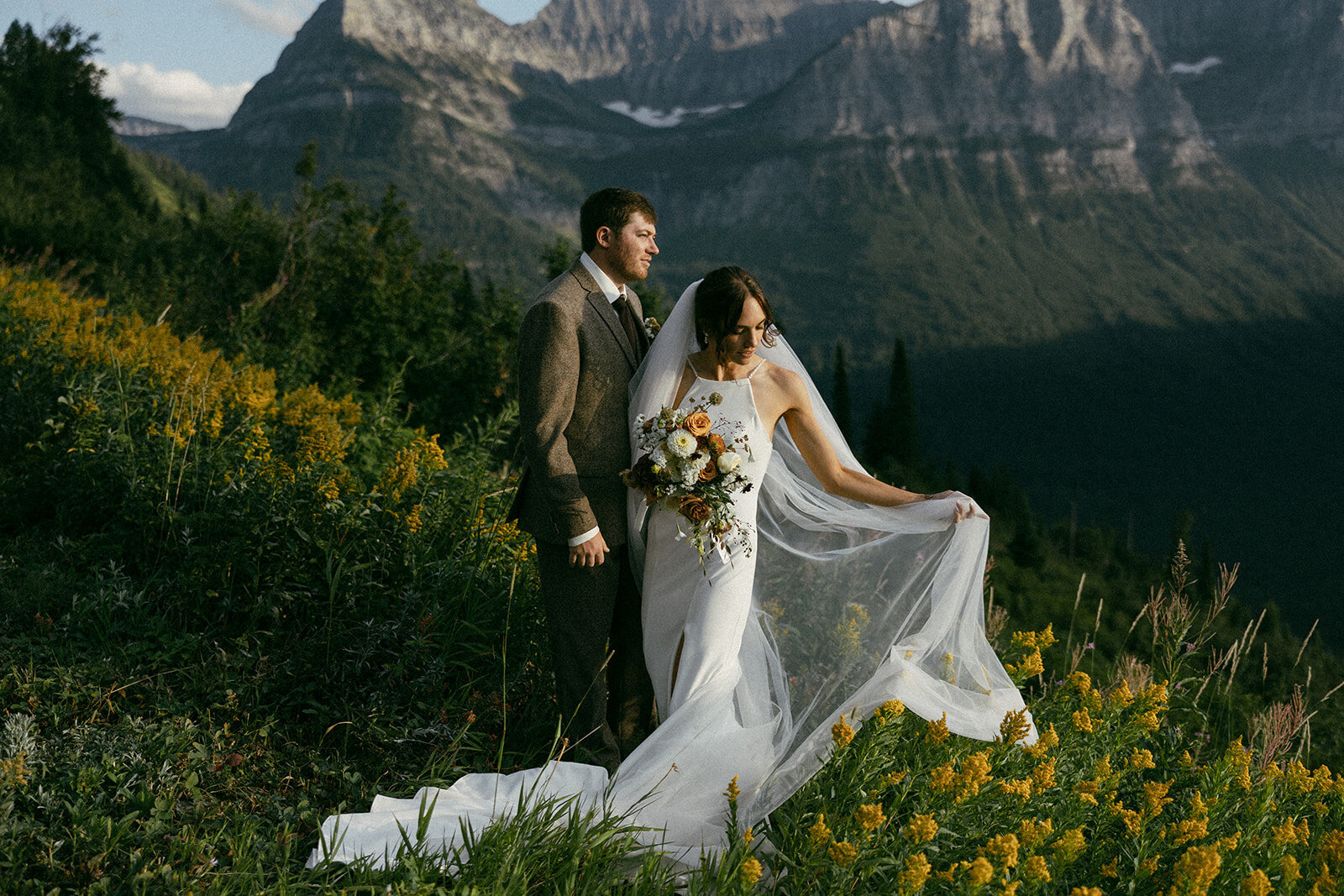 Couple getting married in Glacier National Park Montana, surrounded by yellow summer wildflowers