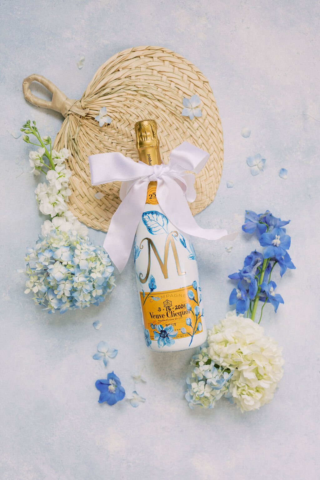 White painted champagne bottle on blue background with hydrangeas