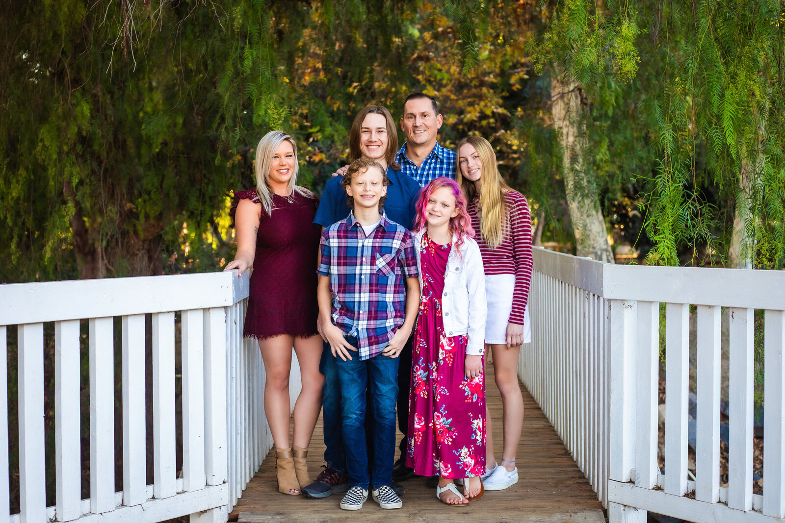 Family Photographer, a family of five stands on a bridge under the trees