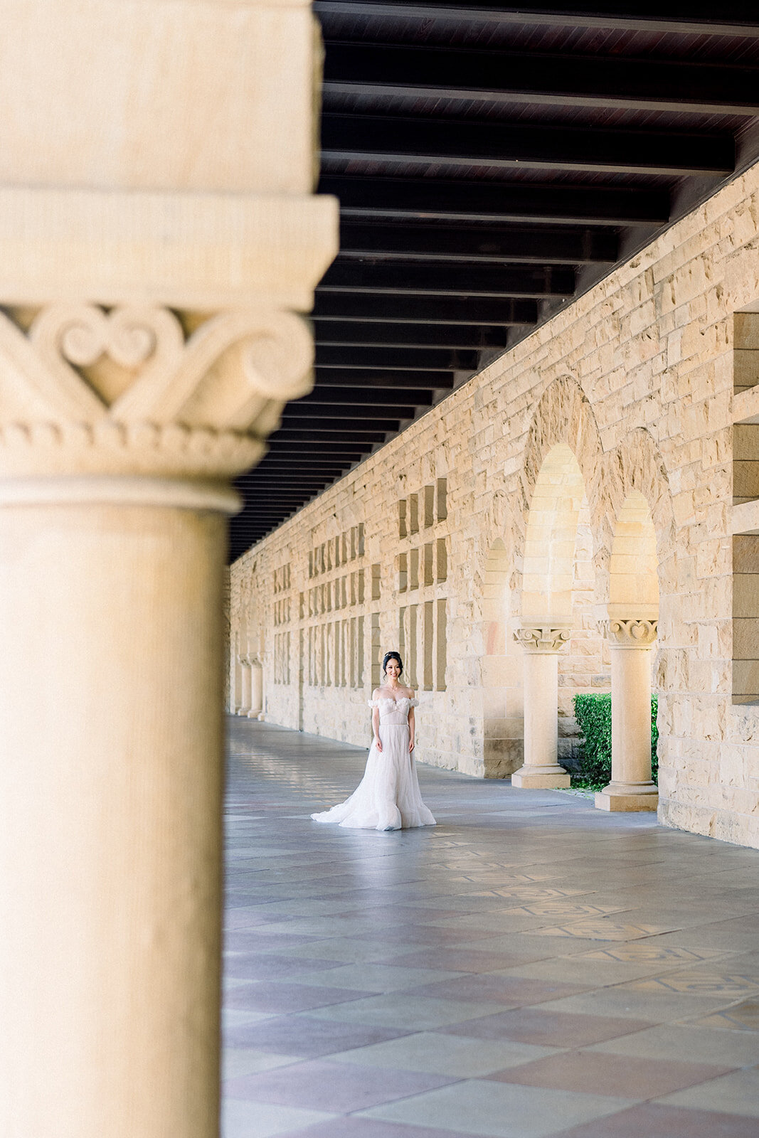 The bride makes her grand entrance, walking through the historic arches of Stanford University on her wedding da