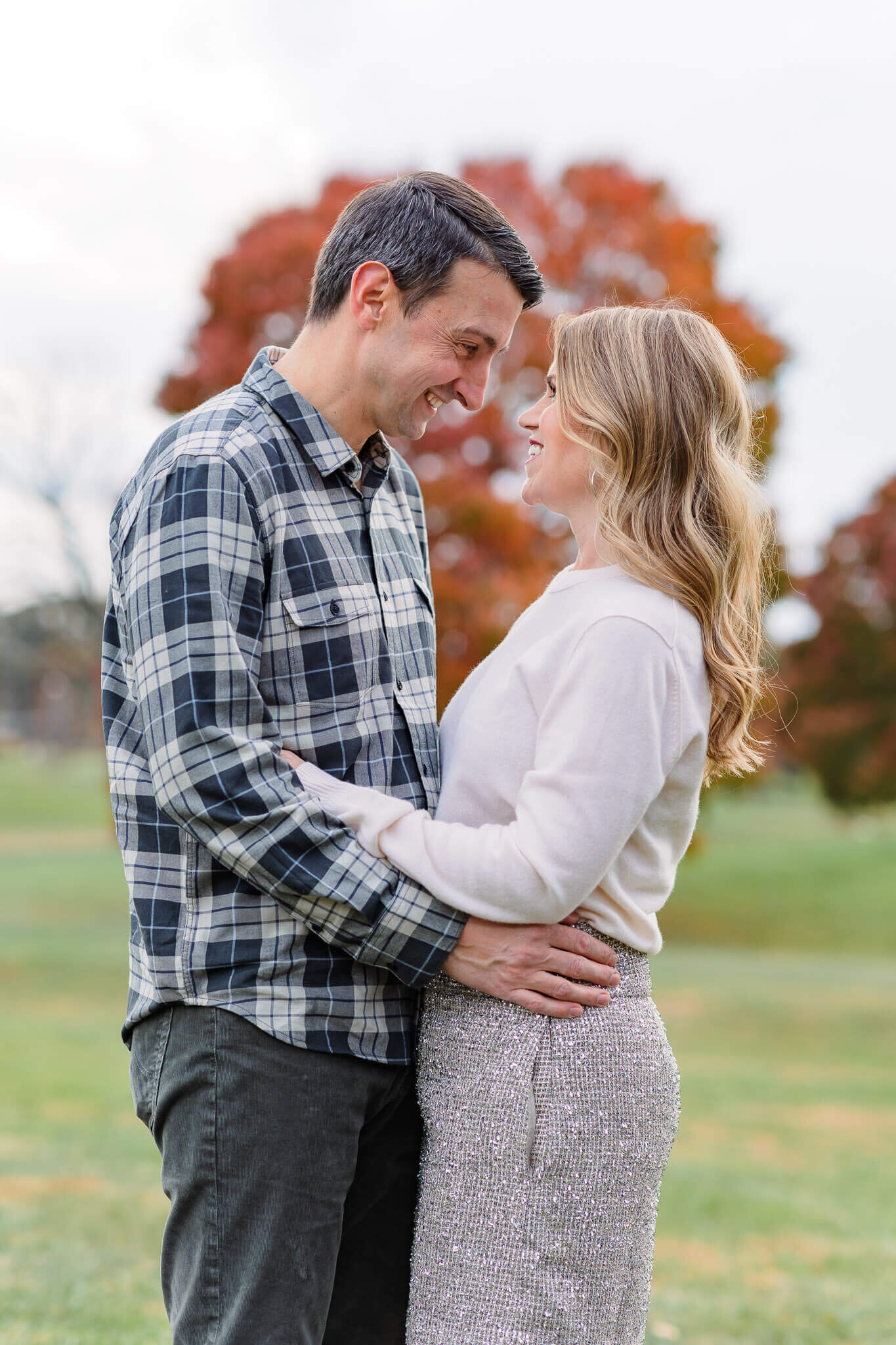 A mom and dad snuggling and smiling at each other.