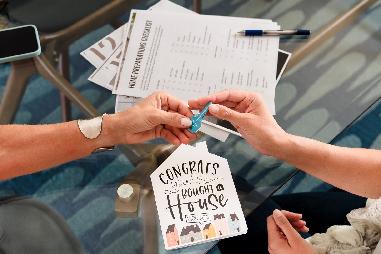 realtor and buyer holding a key, underneath a congrats  card