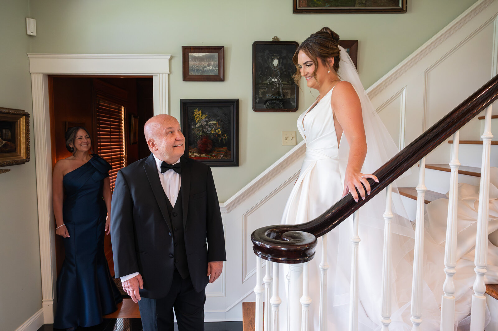 Bride walking down the stairs with her Dad's happy reaction to seeing her in her gown