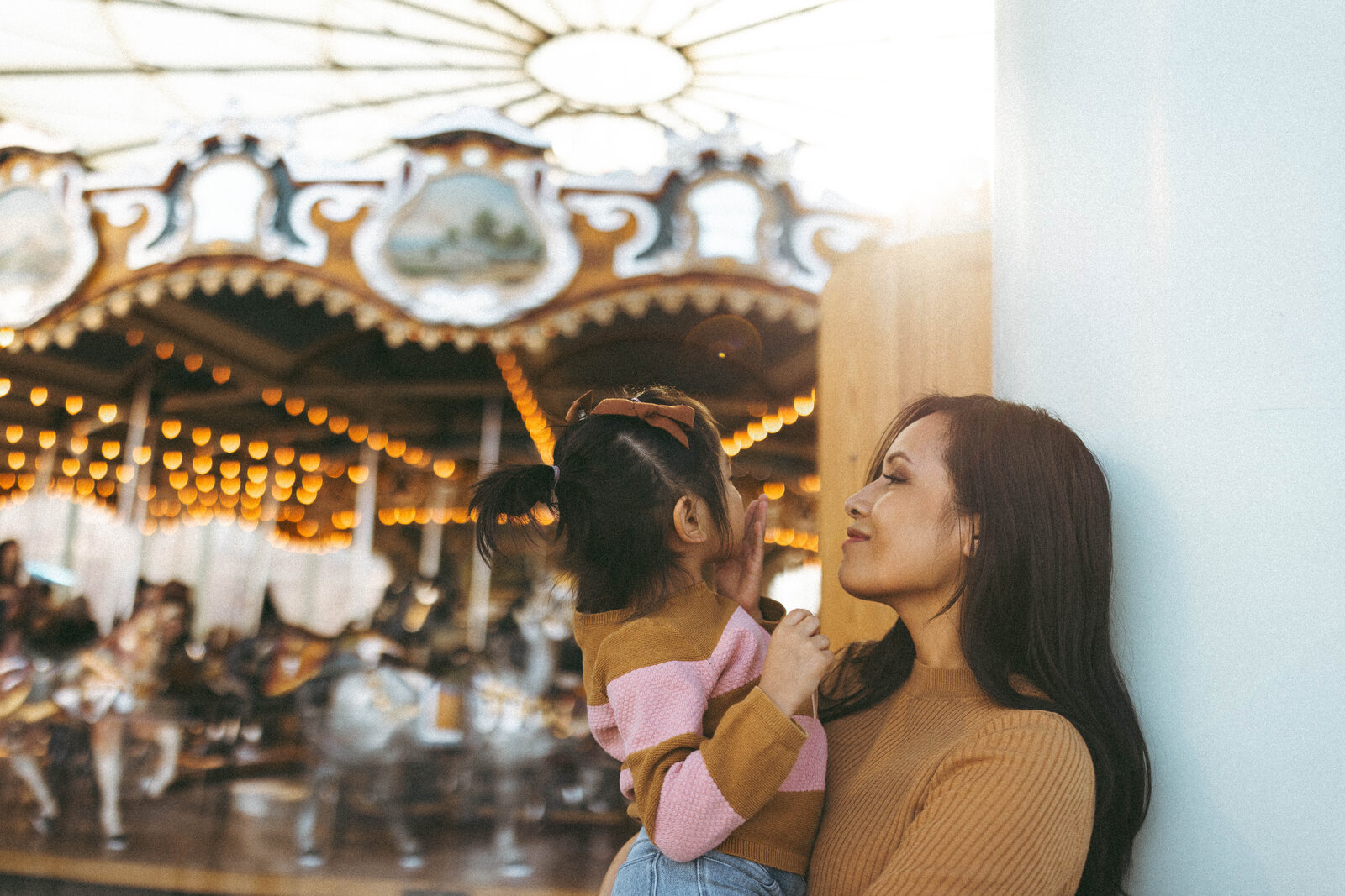 DUMBO brooklyn a mother and daughter cuddling in front of the carousel
