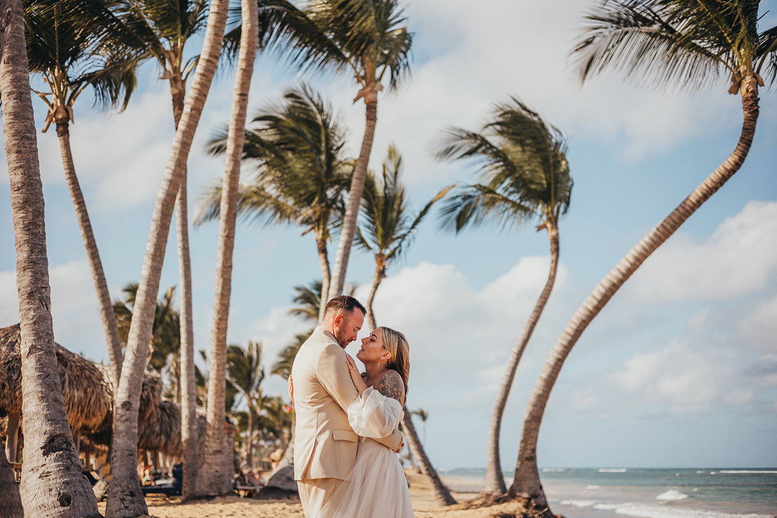 bride and groom embrace beneath a palm tr