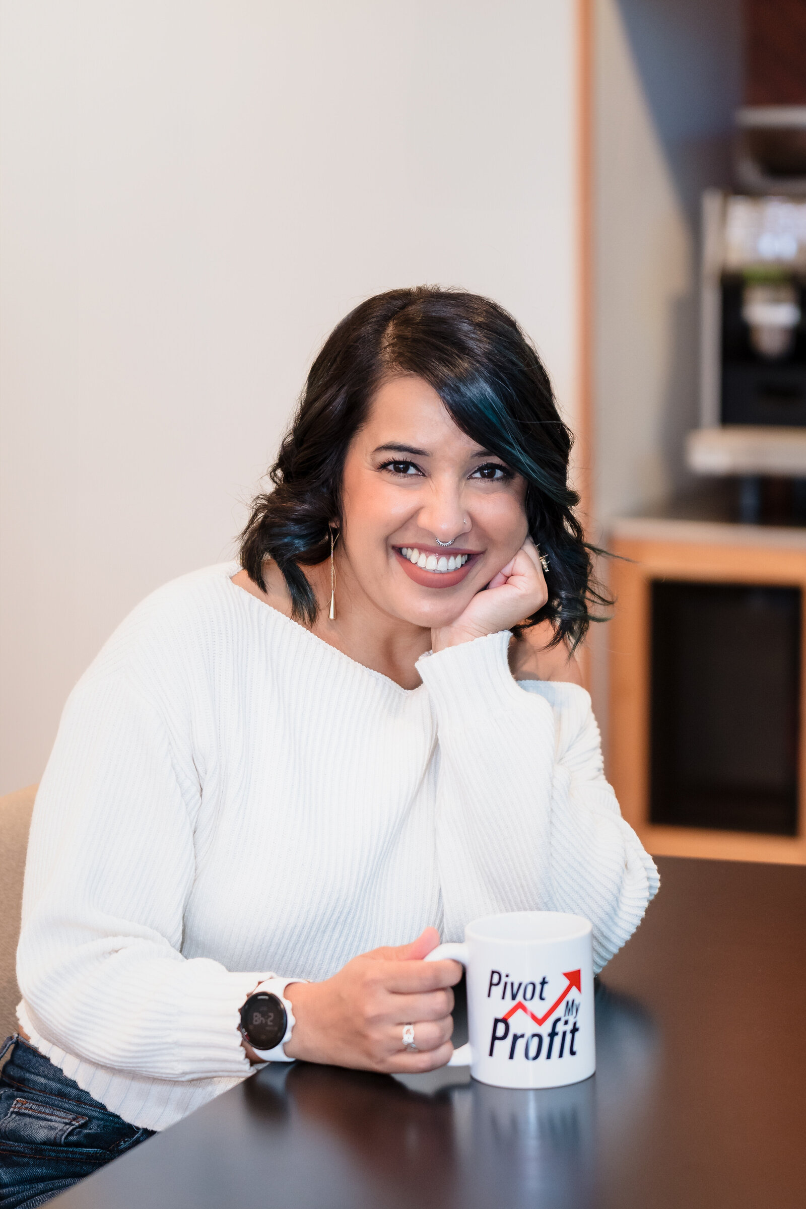 Business Coach poses siting and smiling, holding a coffee mug