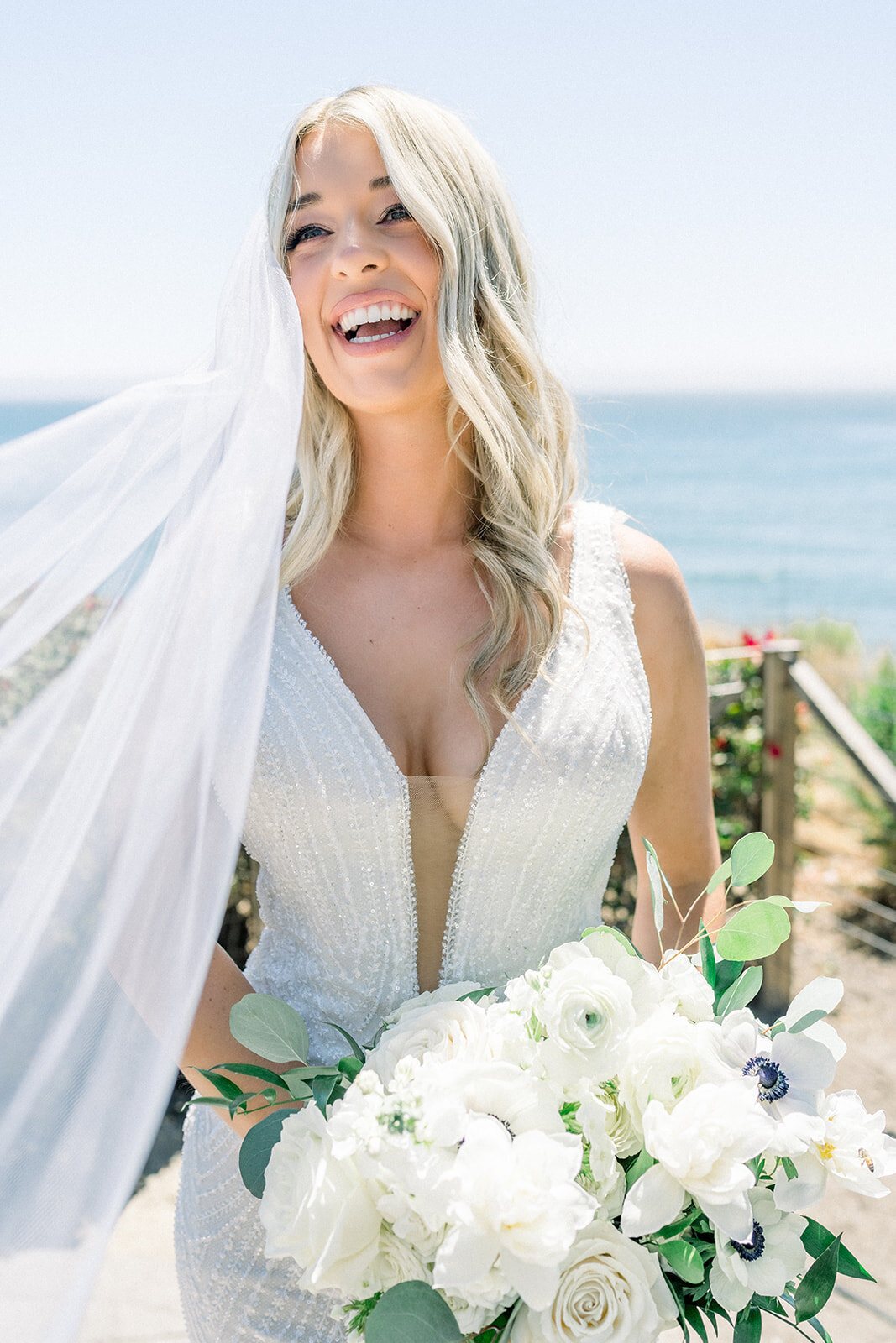 Bride wearing veil holding a white wedding bouquet at Dolphin Bay Resort in Pismo Beach, CA