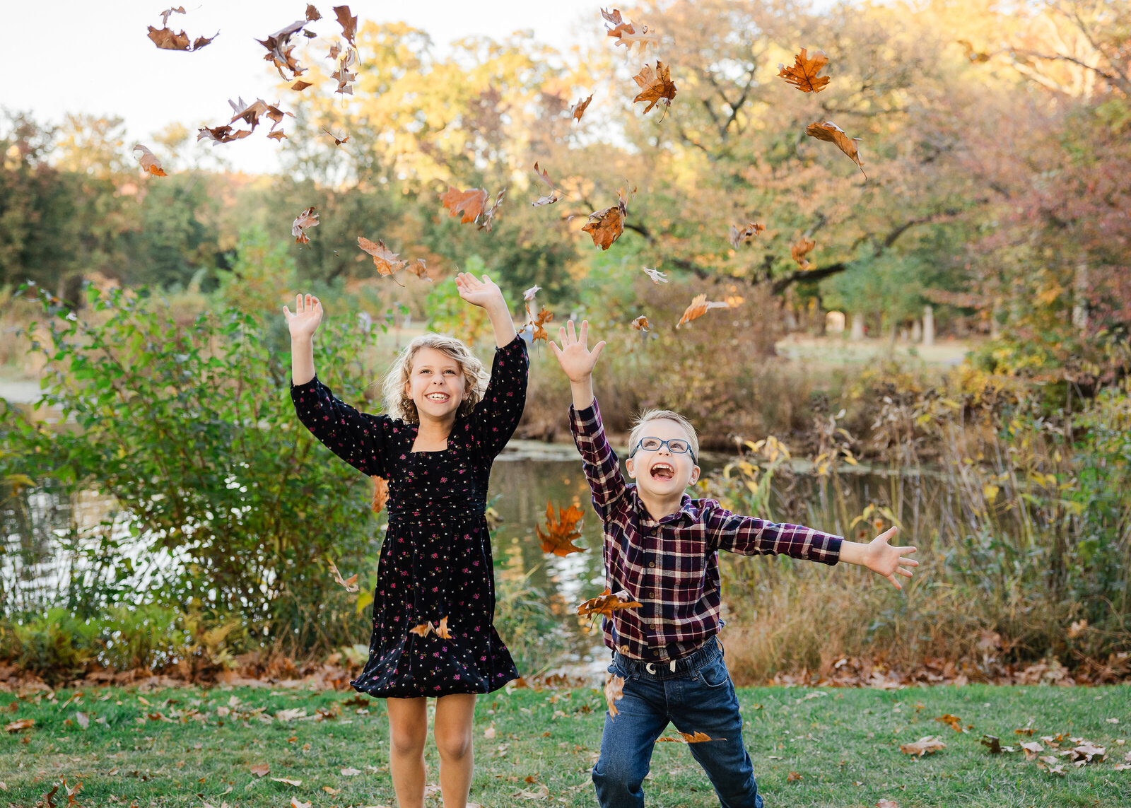 Lifestyle photo of playful siblings throwing leaves at a Union County, New Jersey park in the fall.